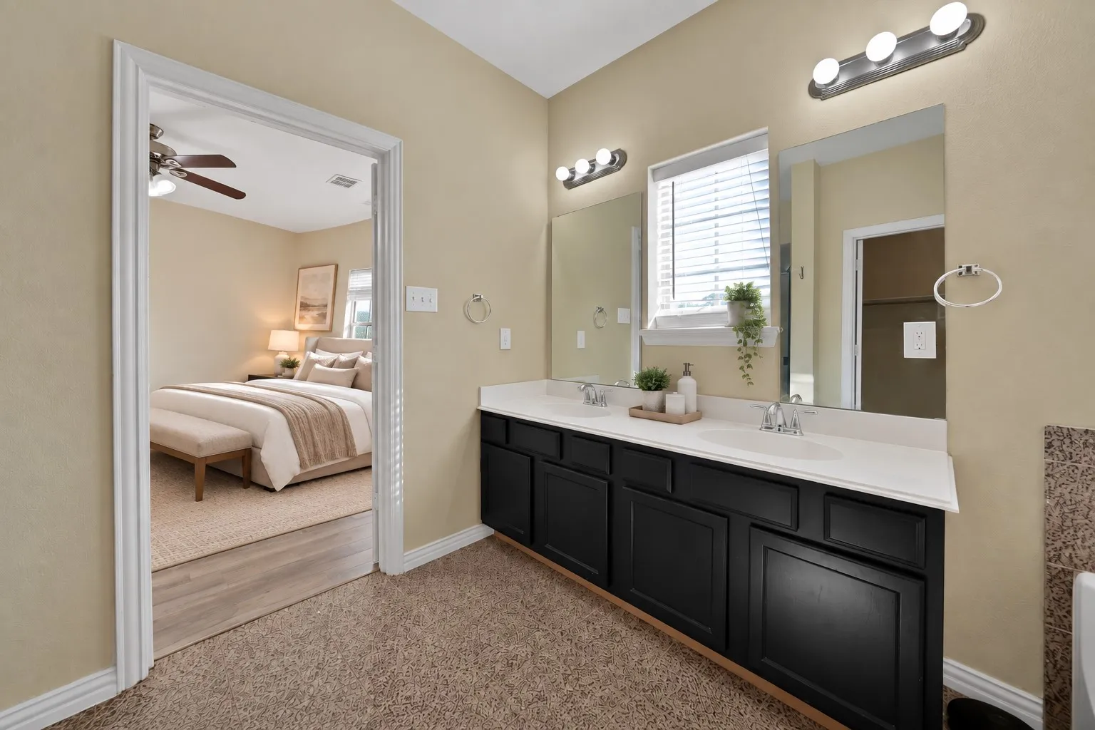 Upstairs primary ensuite bath: Dual-sink vanity with dark cabinetry, two vanity mirrors, and a window for natural light. Opens directly to the upstairs primary bedroom.