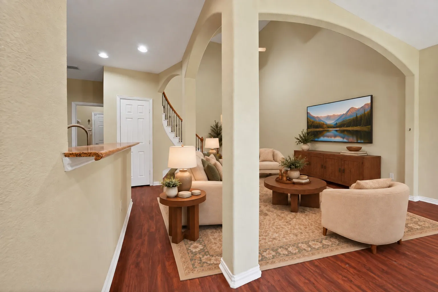 Arched openings and a decorative column frame the living room. Breakfast bar and hallway access to the main level. Virtually Staged