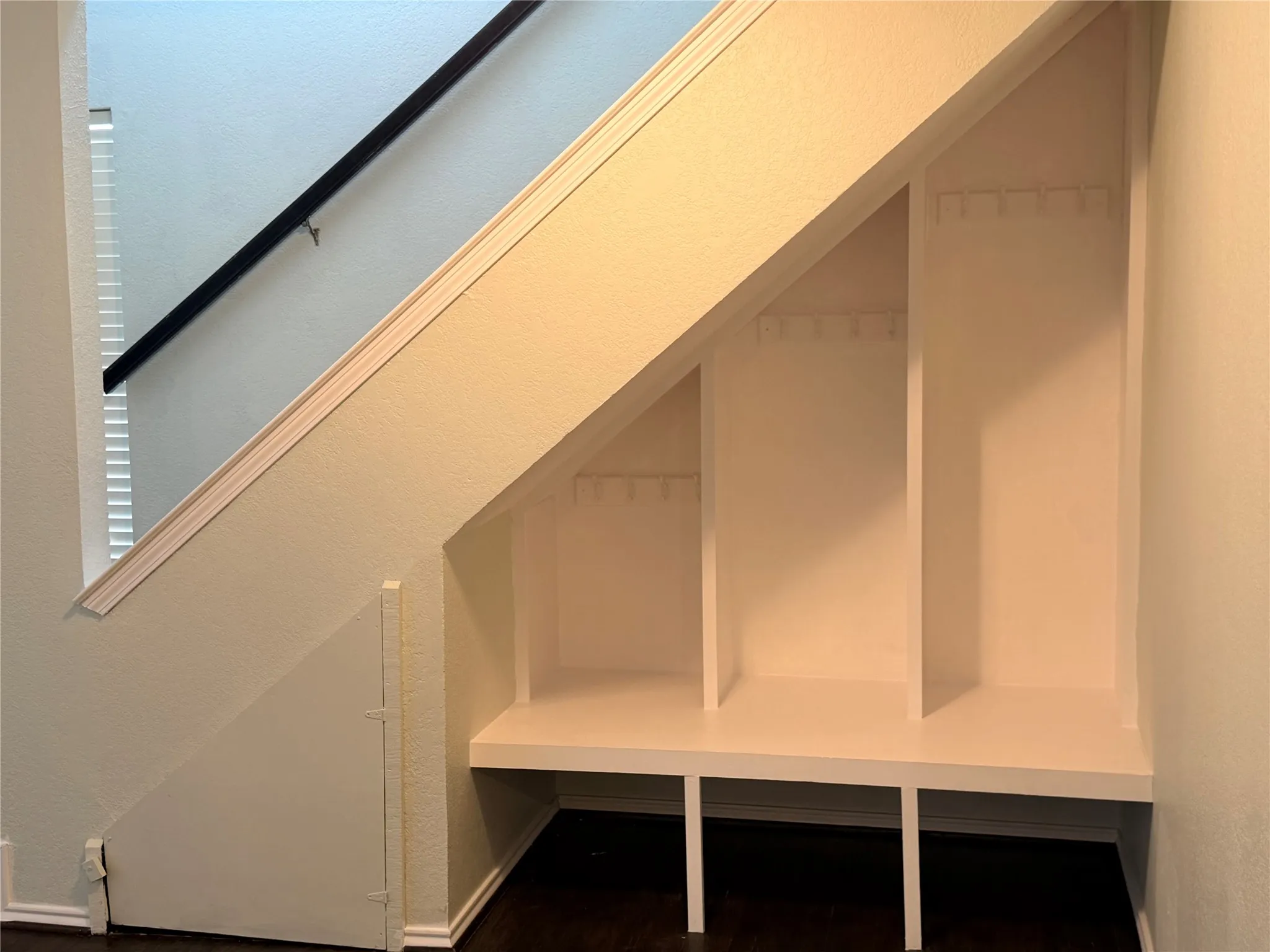 Built-in under-stair storage featuring multiple compartments, integrated shelving, and coat hooks