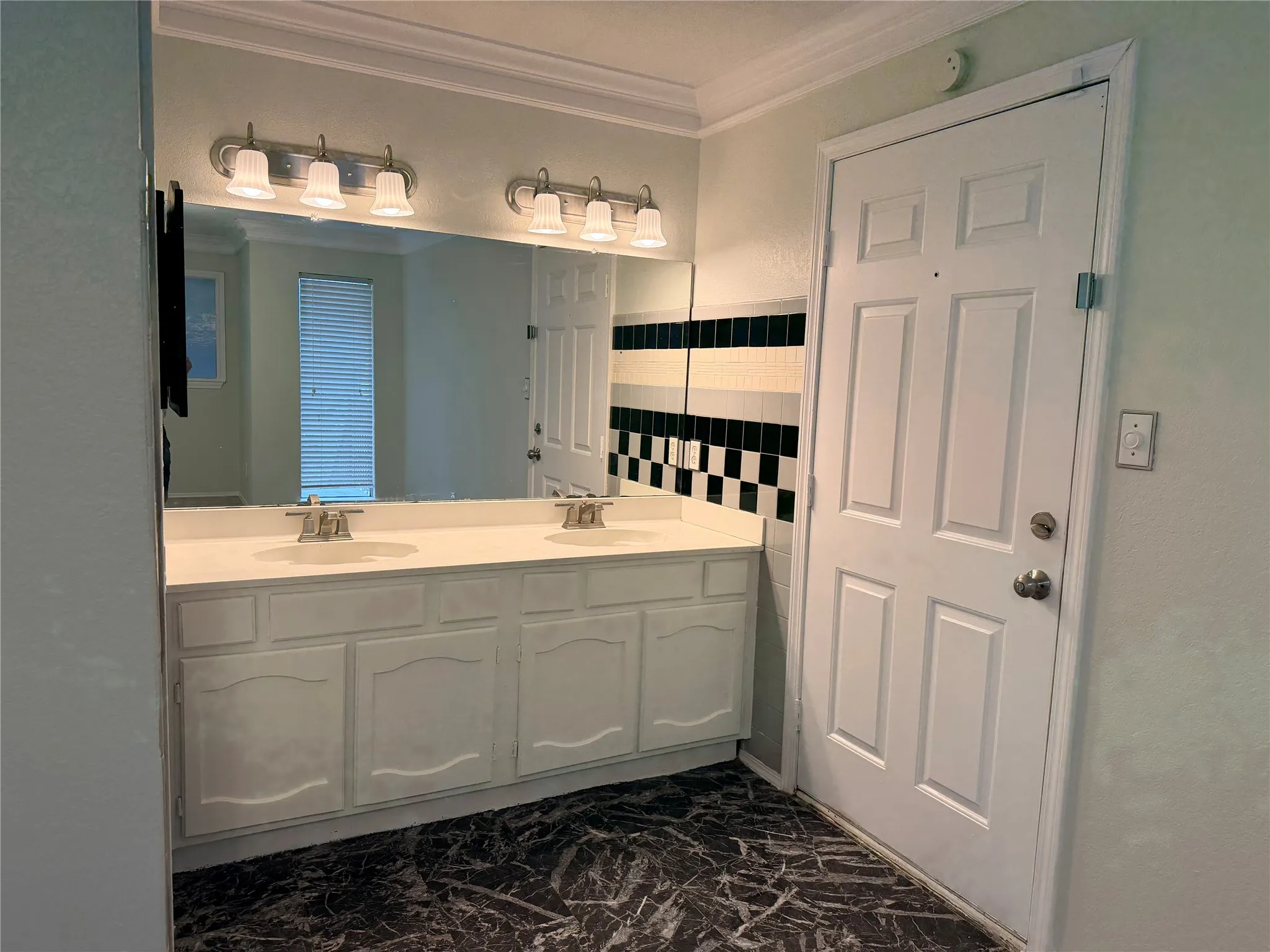 Double vanity with integrated sinks, white cabinetry, and a large wall-mounted mirror