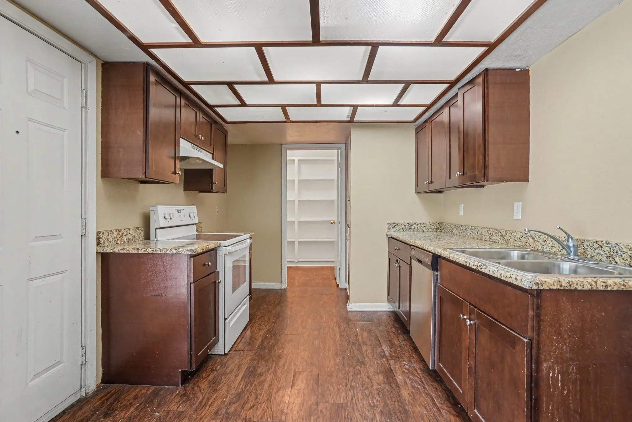 Kitchen featuring wood-finish flooring, wood cabinetry, stone countertops, and a double basin sink