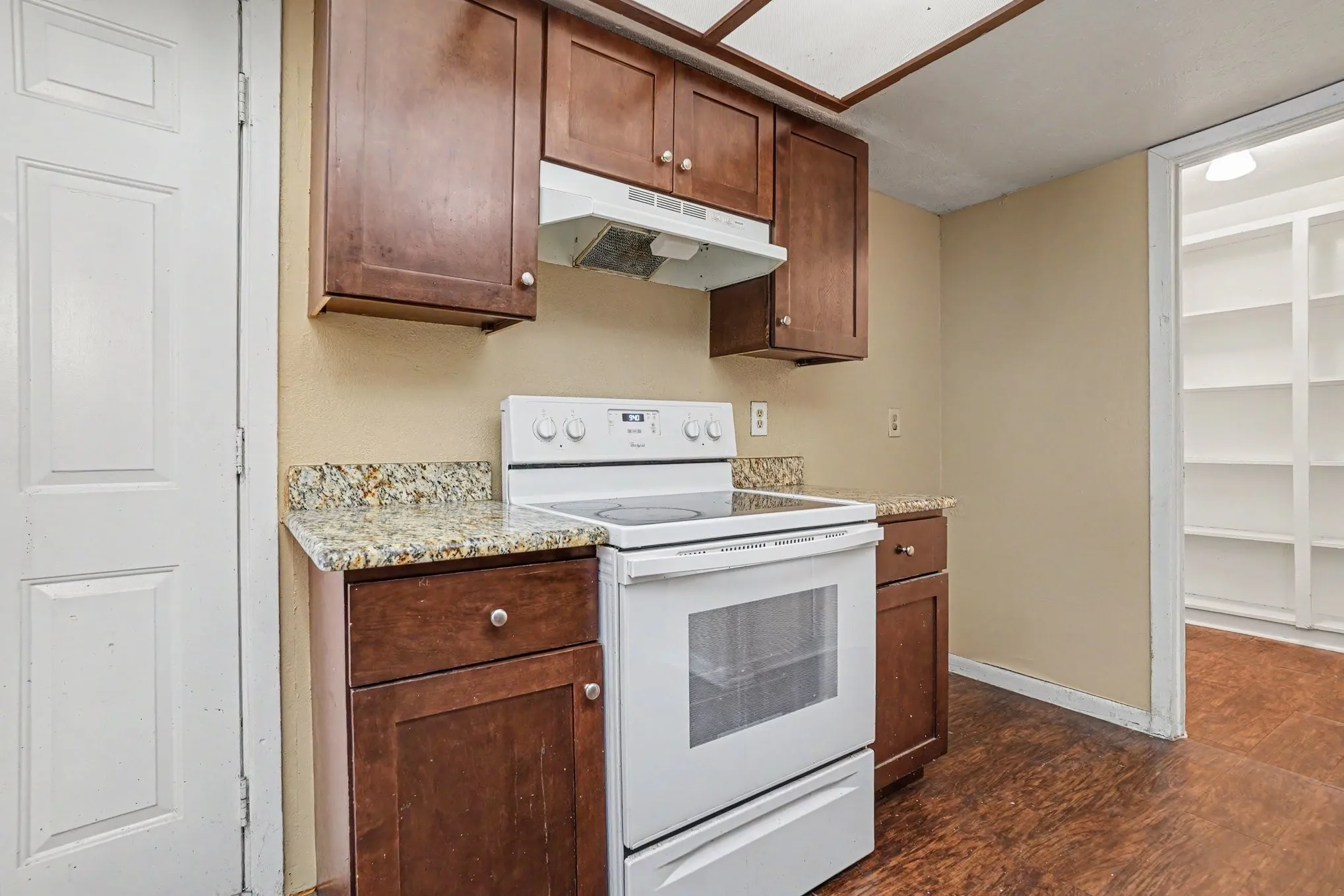 Kitchen featuring wood-finish cabinetry, granite-style countertops, an electric range, and a built-in pantry with shelving