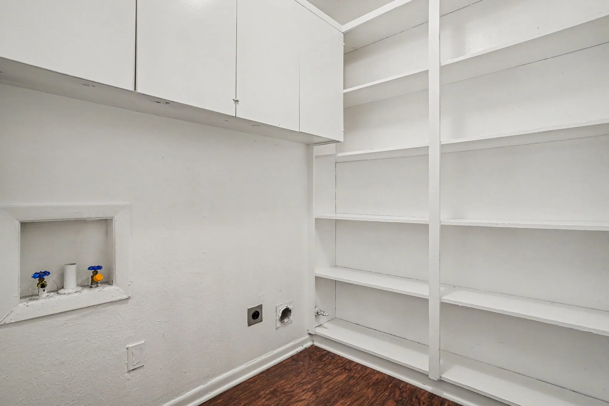 White built-in cabinetry, extensive built-in shelving, wood-finish flooring, and laundry hookups