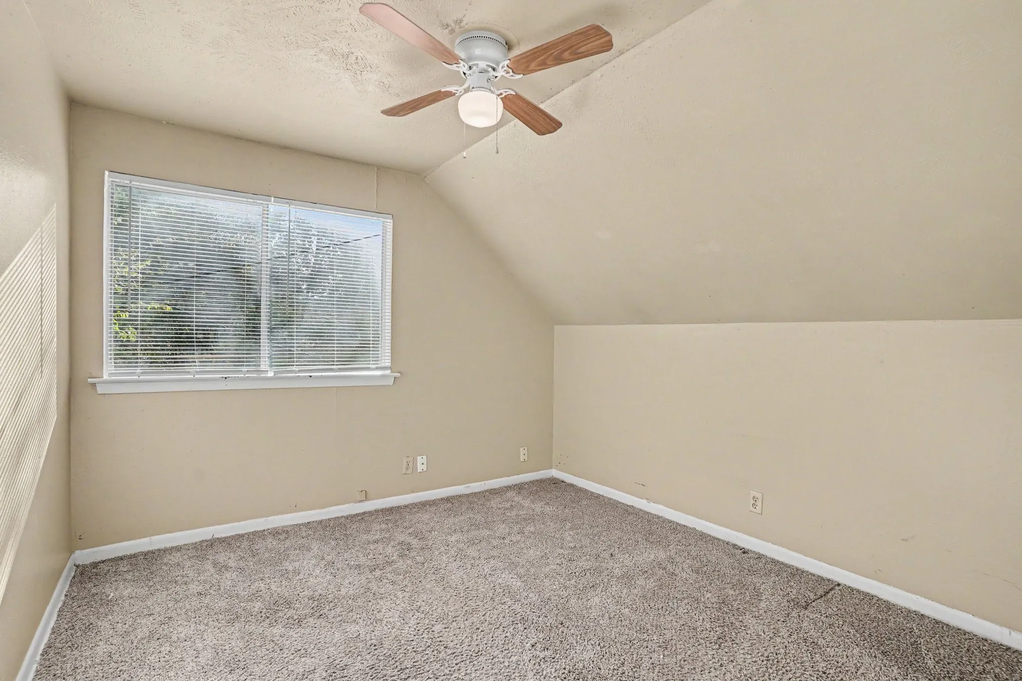 Room featuring sloped ceilings, carpet flooring, a window with blinds, and a ceiling fan with light fixture