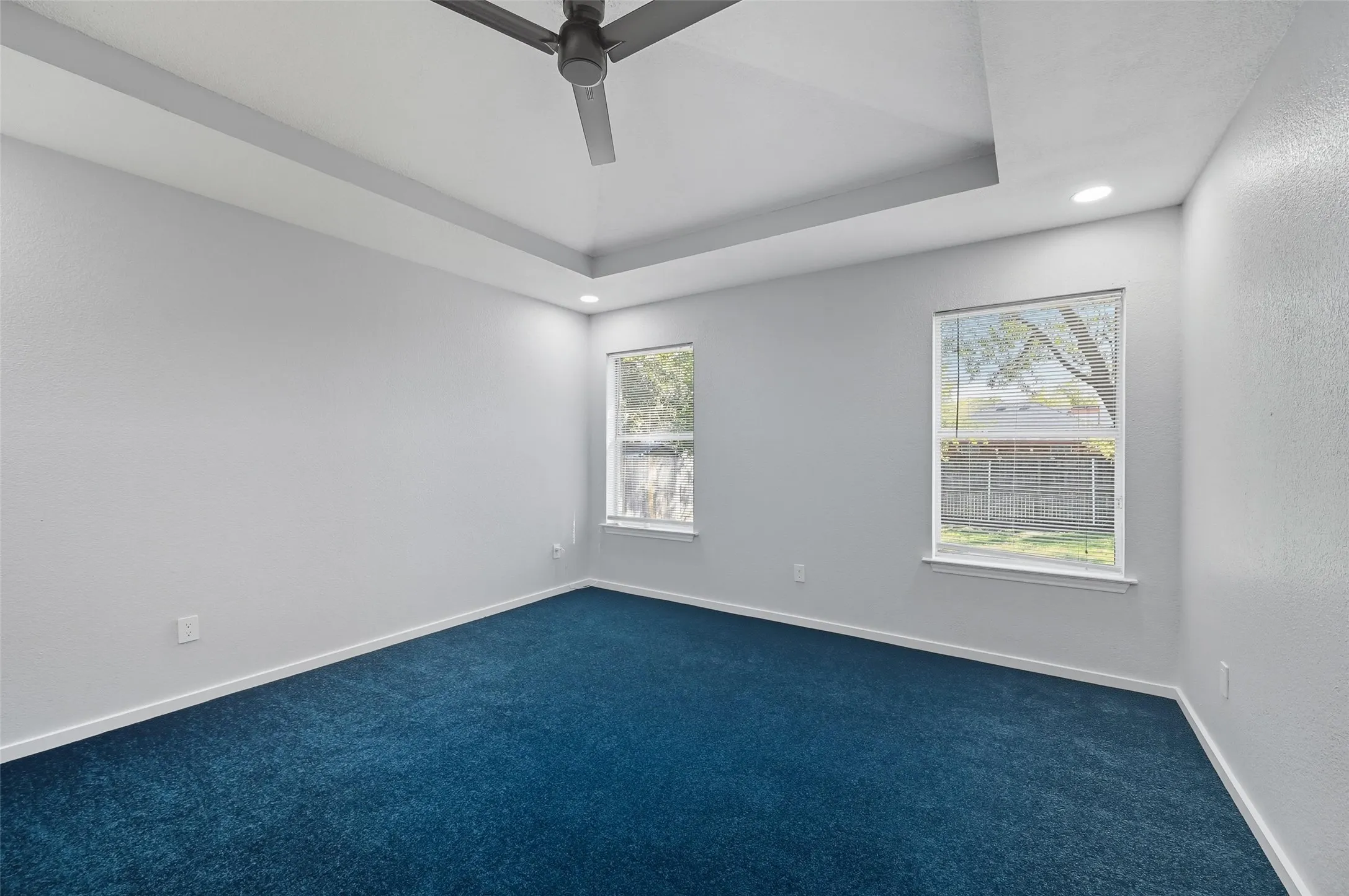 Spacious Primary Bedroom with fresh paint, recessed dimmable lighting, ceiling fan and window coverings.