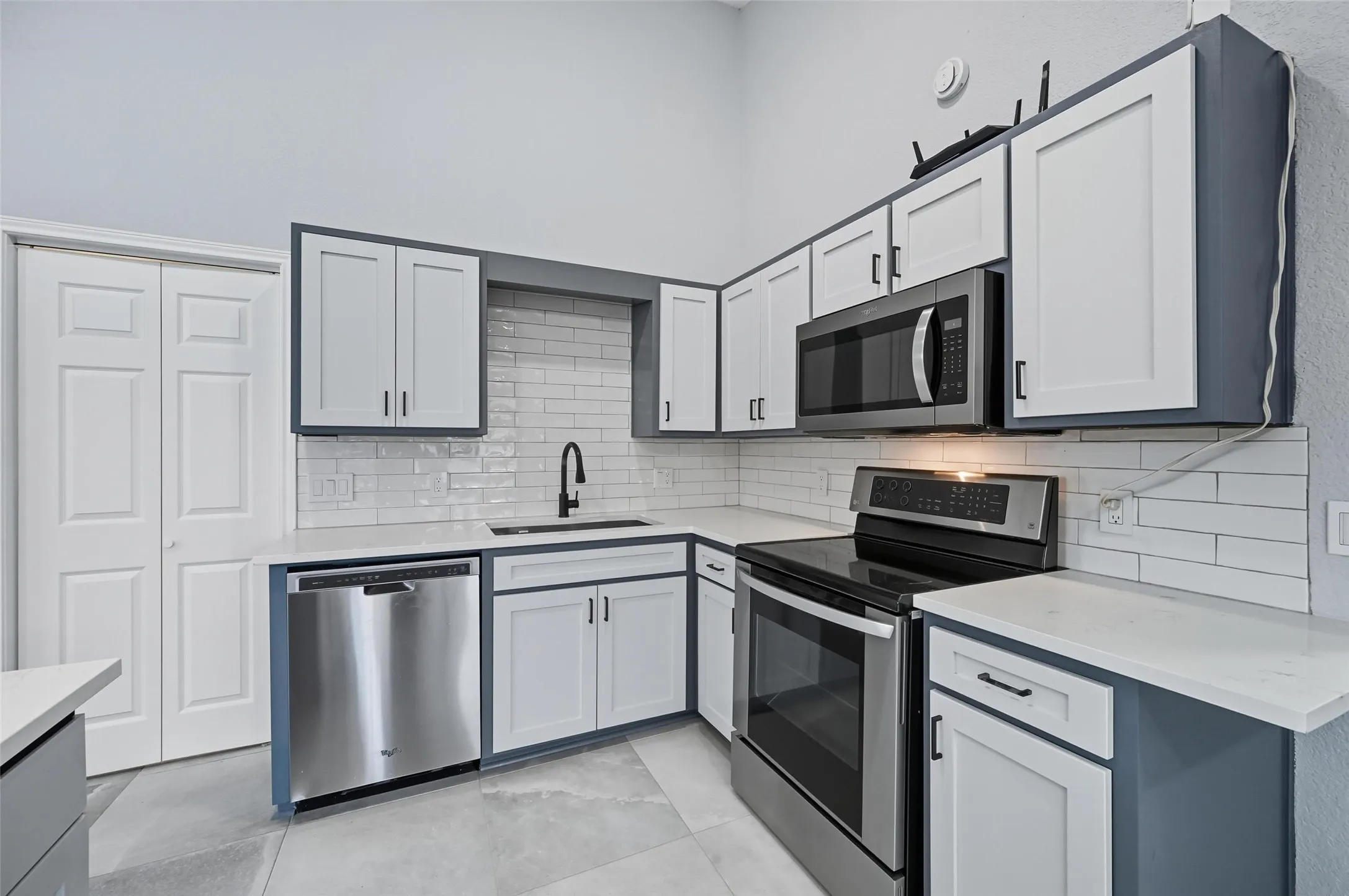 Kitchen featuring new microwave oven, a range cooktop, dishwasher, custom cabinets, self closing drawers, light counters, and tile flooring.