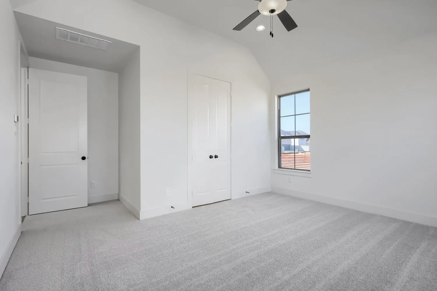 Vaulted ceiling with a ceiling fan and recessed lighting, light gray carpet, and a multi-pane window