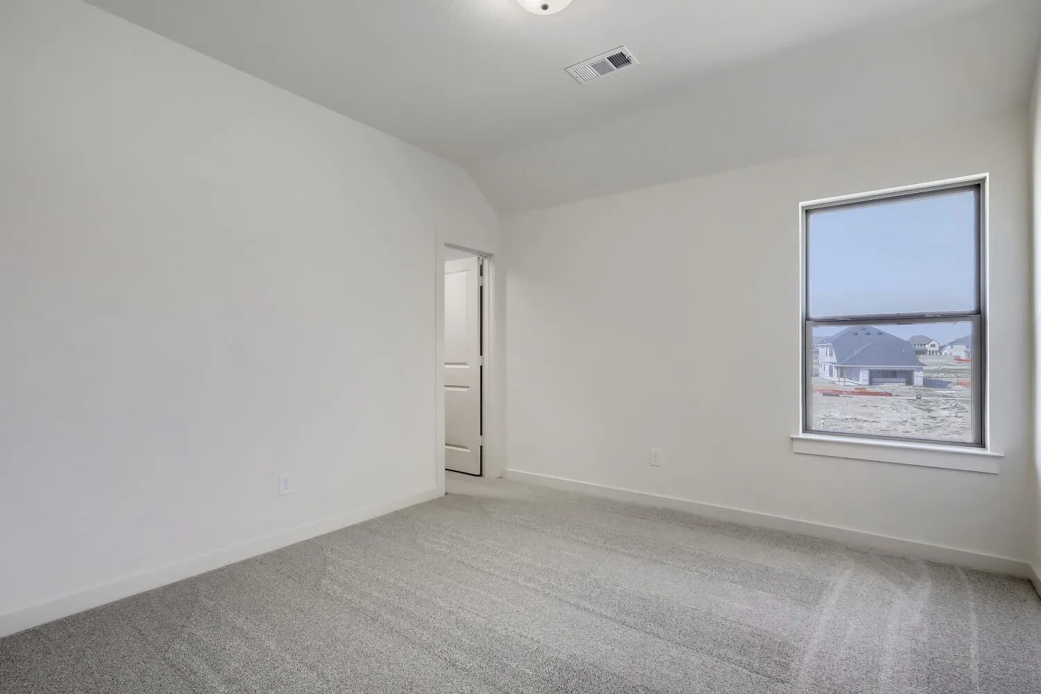 Neutral interior room featuring light gray carpet, white walls, and a single window with a white frame