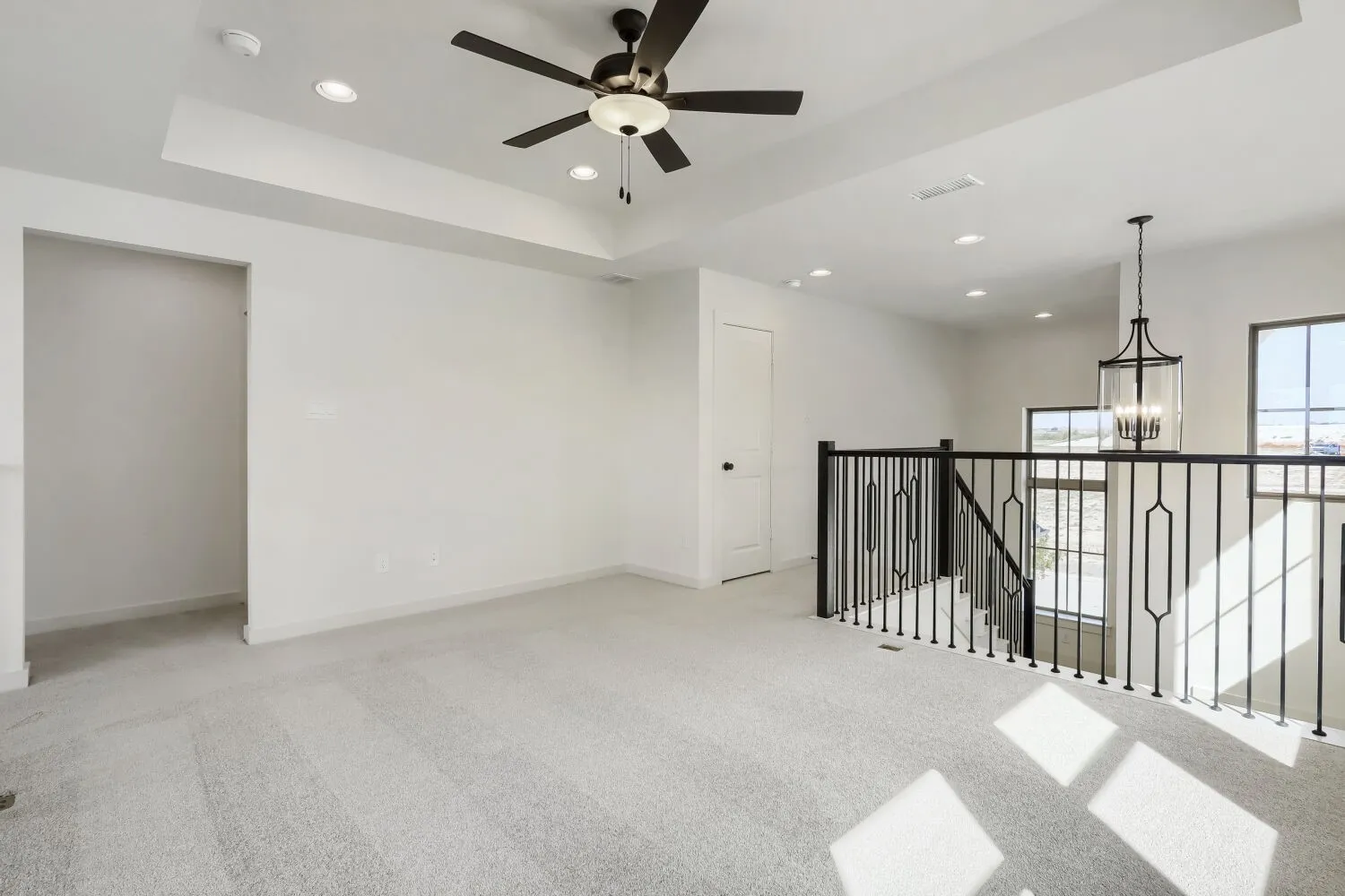Carpeted loft area featuring a tray ceiling, recessed lighting, and a ceiling fan