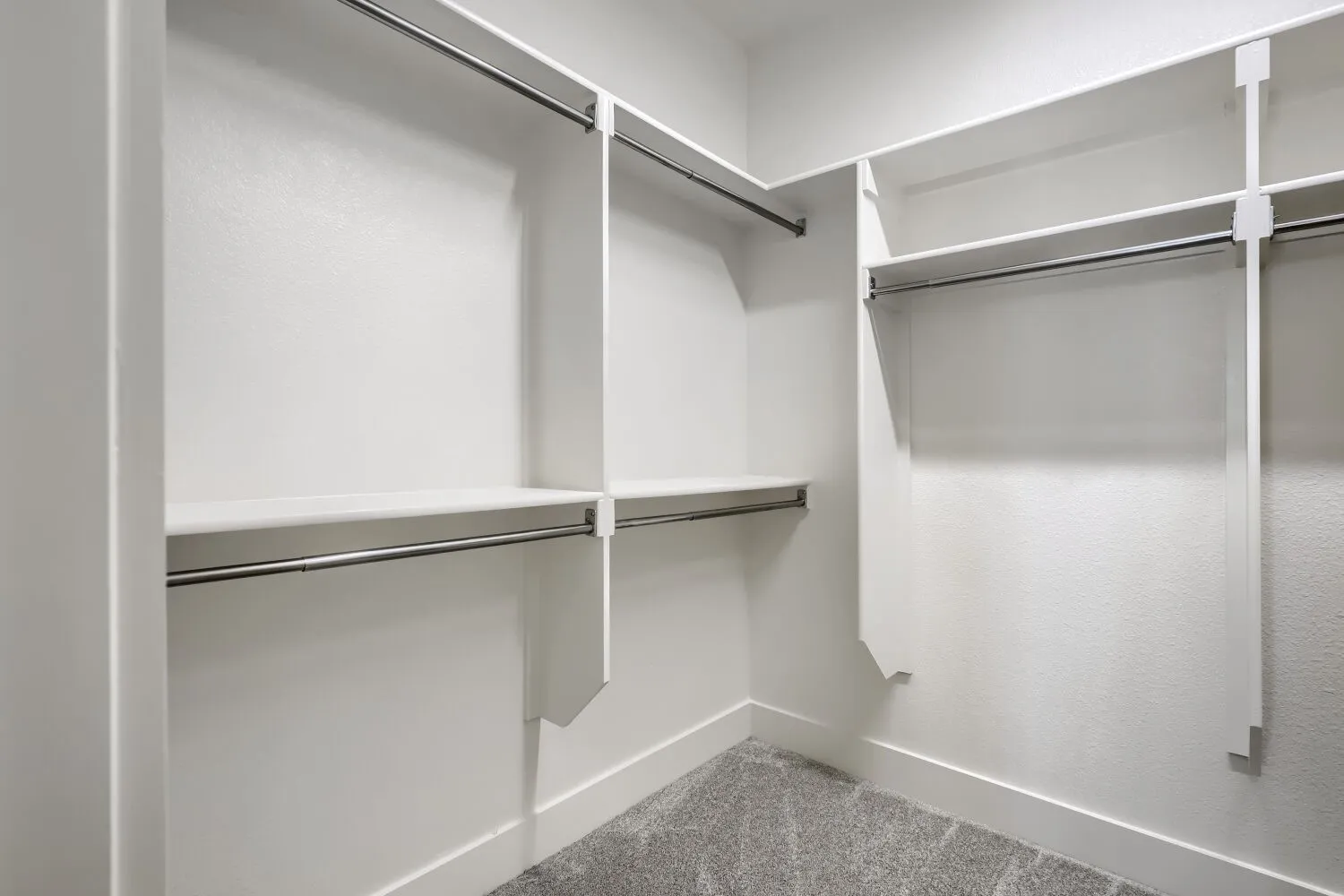 Spacious walk-in closet featuring custom shelving with multiple storage levels, dual hanging rods for extended wardrobe organization, and neutral finishes throughout