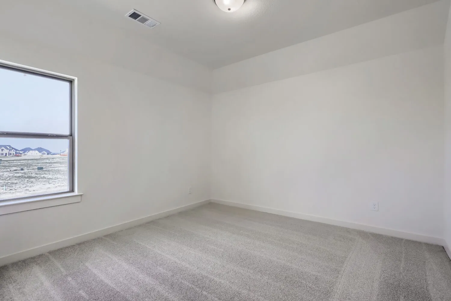 Bright secondary bedroom featuring neutral wall finishes, new carpeting with geometric pattern detail, and large window with natural light exposure and distant landscape views