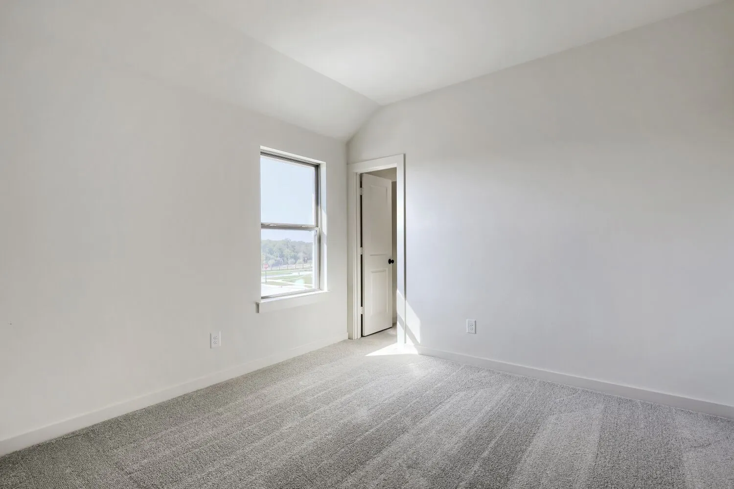 Carpeted room with a single window, white walls, and a vaulted ceiling