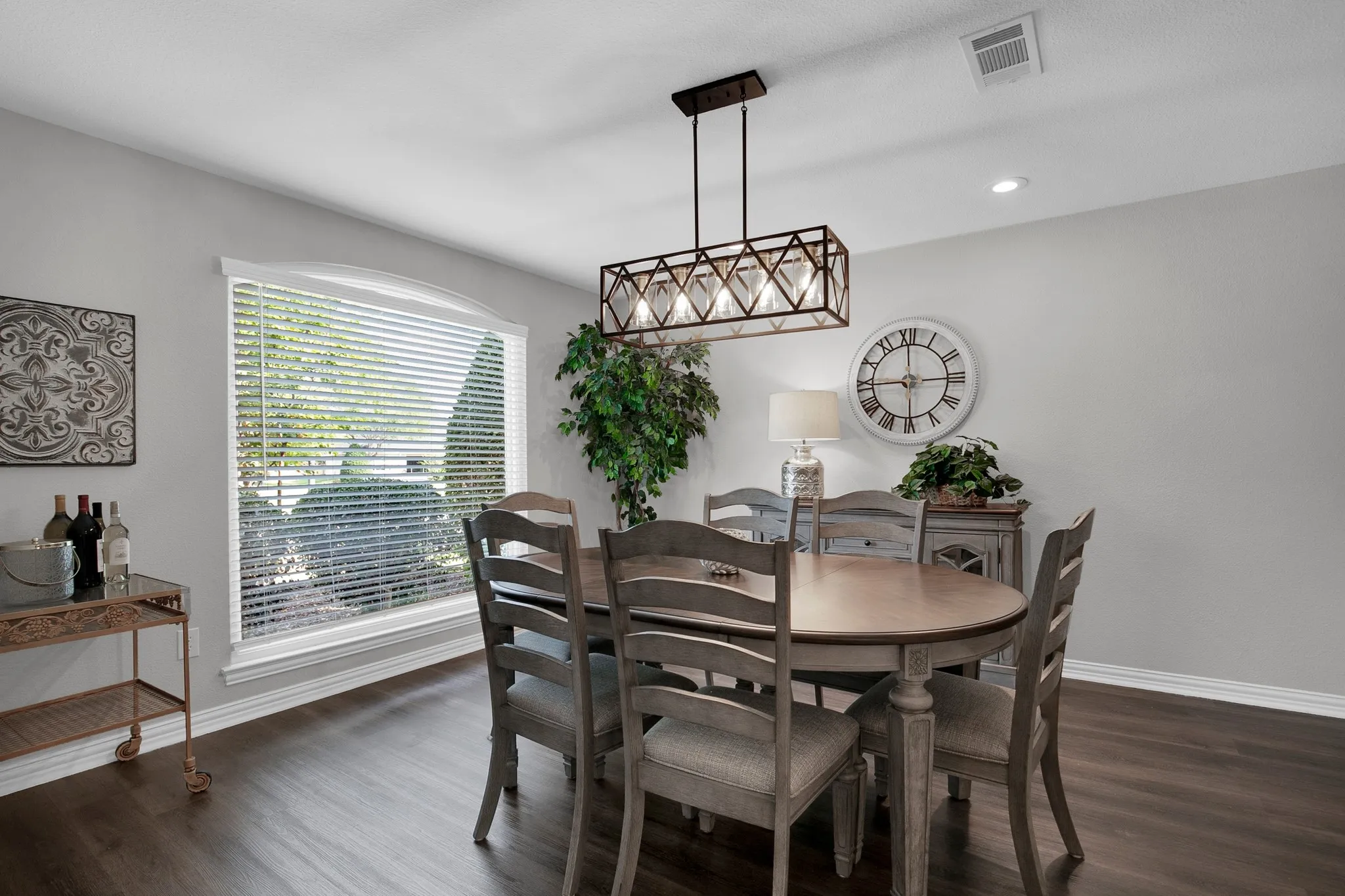 Dining space featuring dark wood-finish flooring, a large arched window, and a linear chandelier
