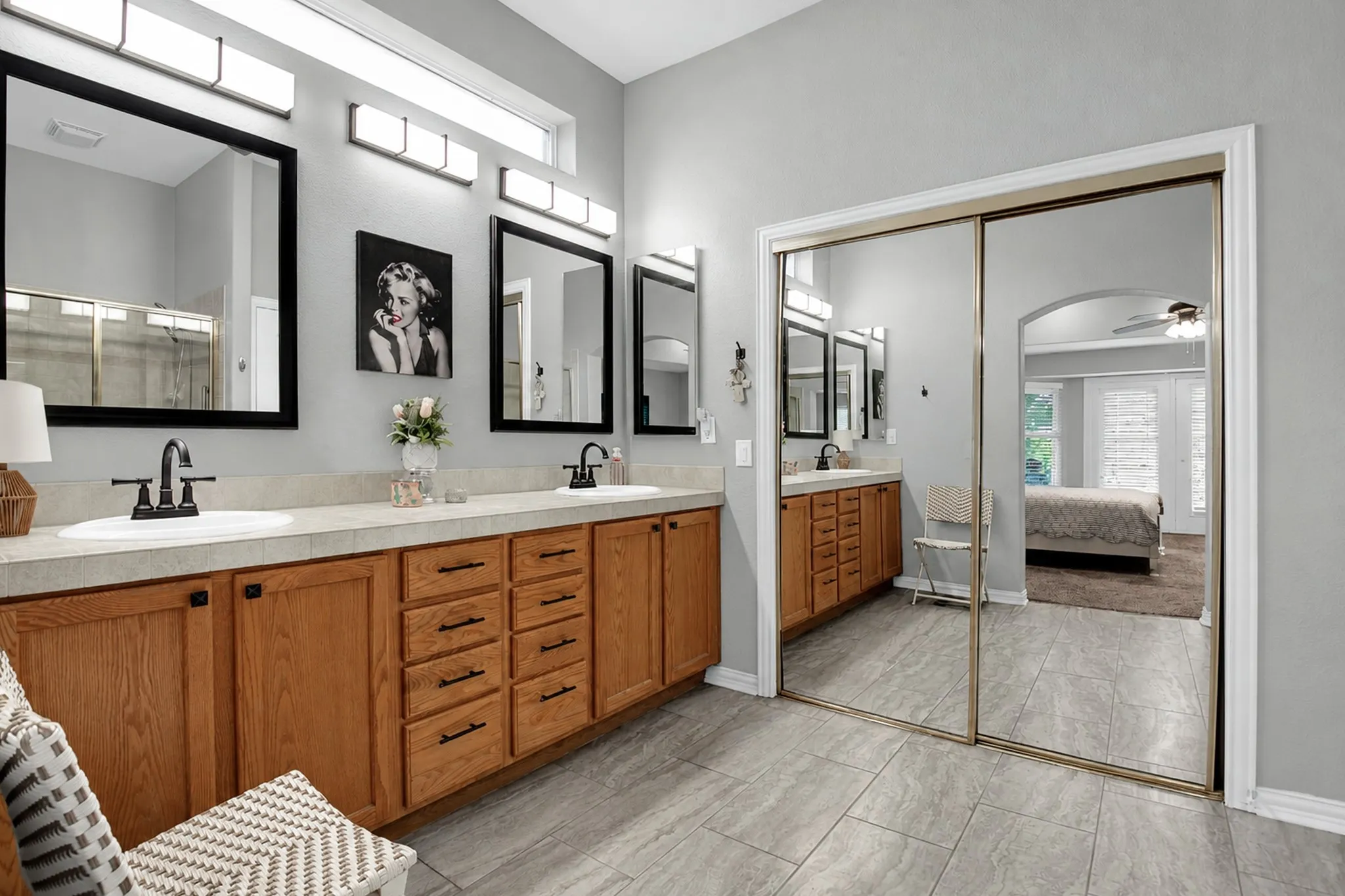 Dual vanity with wood-finish cabinetry, integrated sinks, and black fixtures