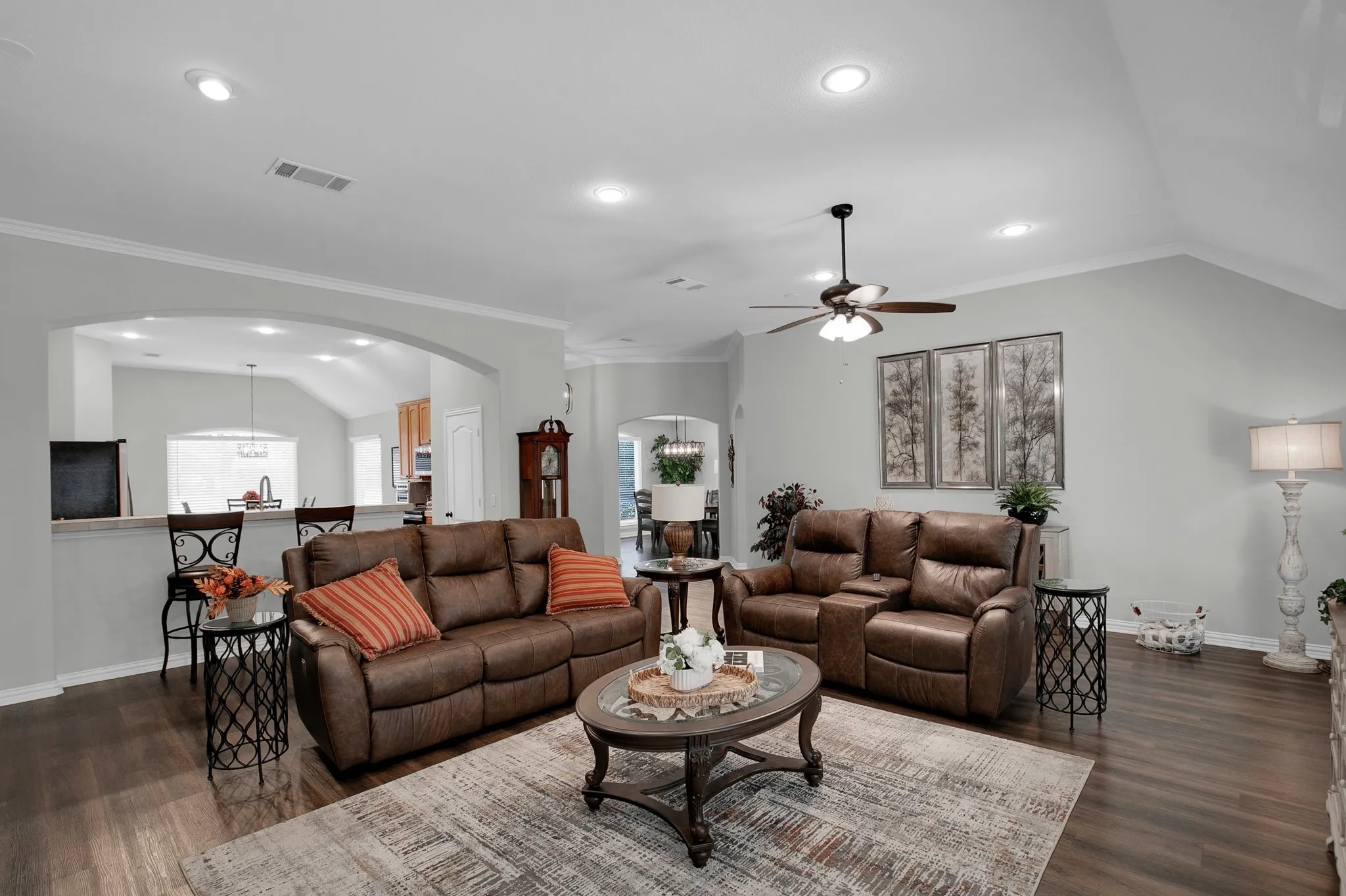 Spacious living area featuring wood-finish flooring, a vaulted ceiling, recessed lighting, and a ceiling fan