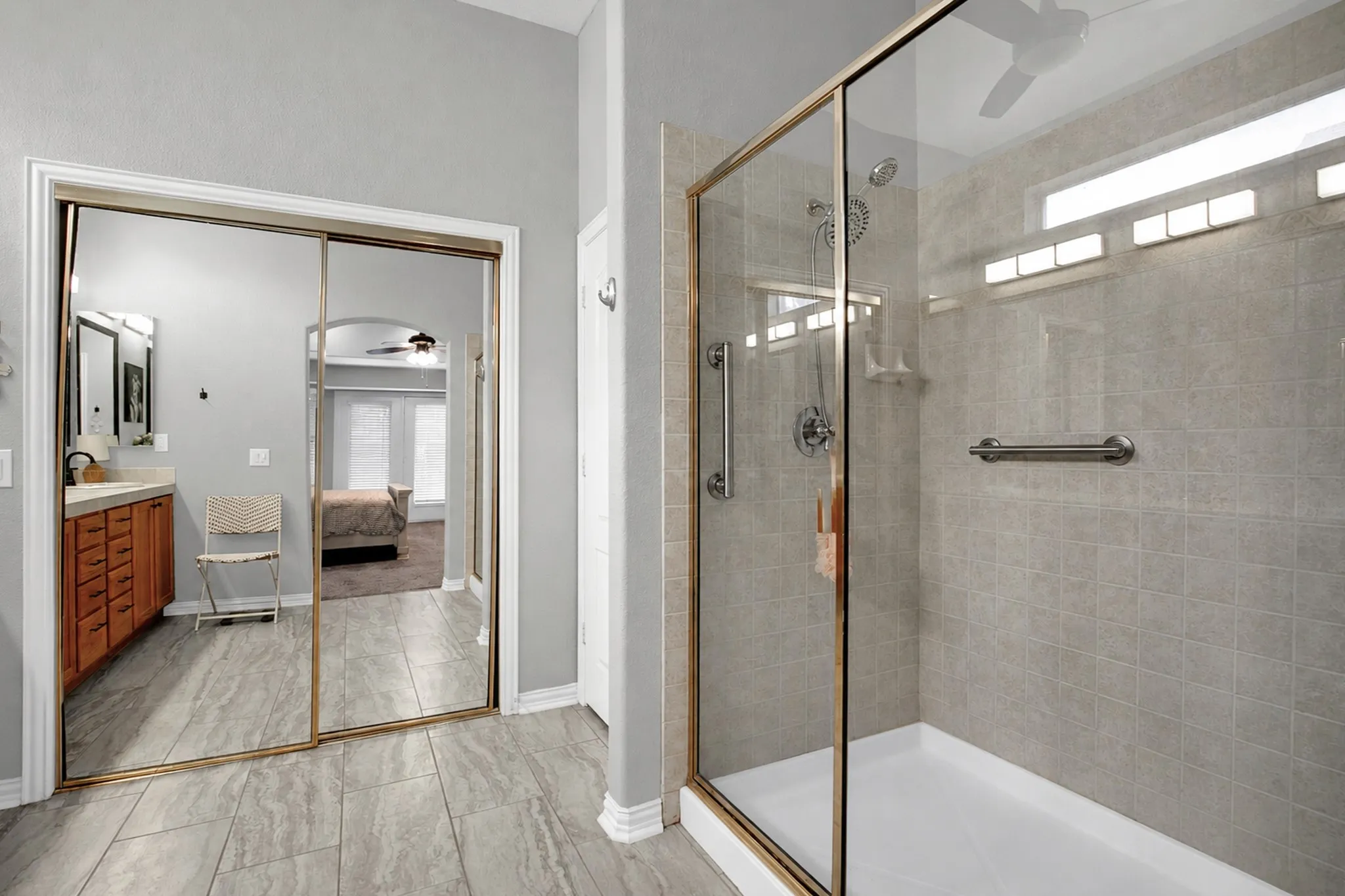 Glass-enclosed shower with subway tile surround, integrated grab bars, and a transom window