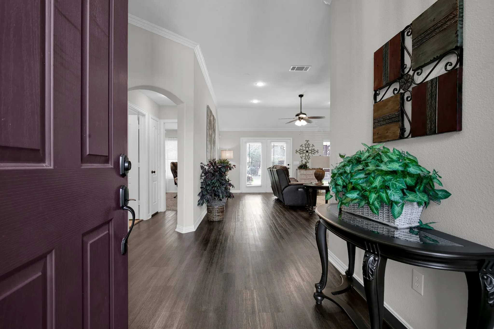 Entryway featuring a paneled front door, wood-finish flooring, an arched doorway, and crown molding