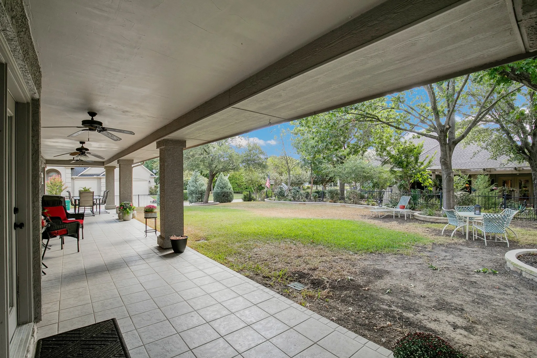Covered patio with tiled flooring, ceiling fans, and structural columns
