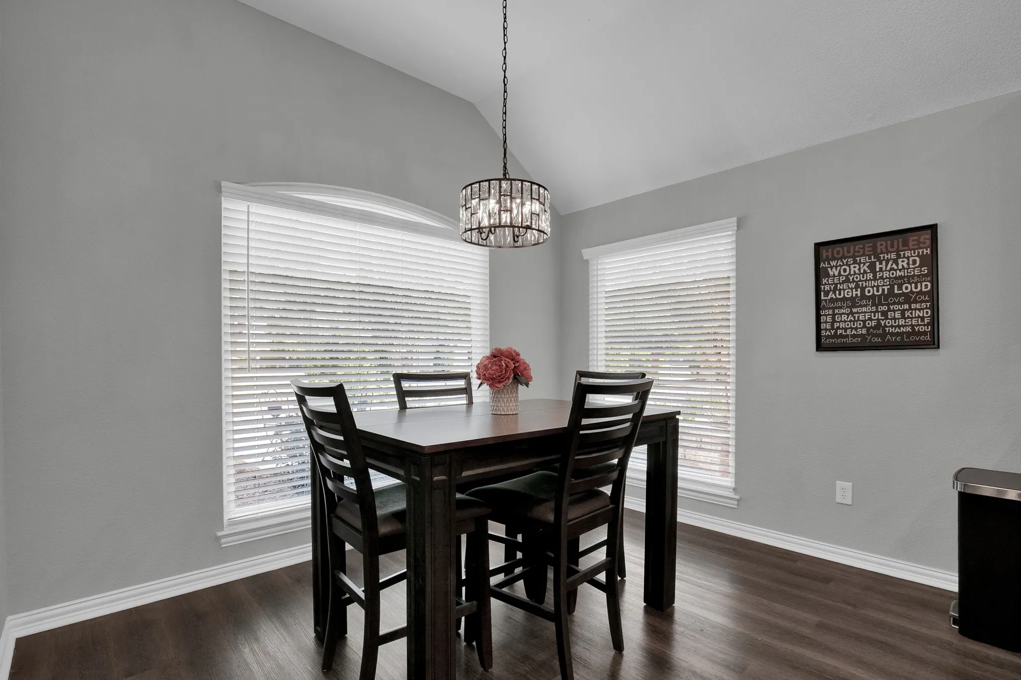 Vaulted ceiling, wood-finish flooring, two large windows, elegant chandelier, neutral wall tones