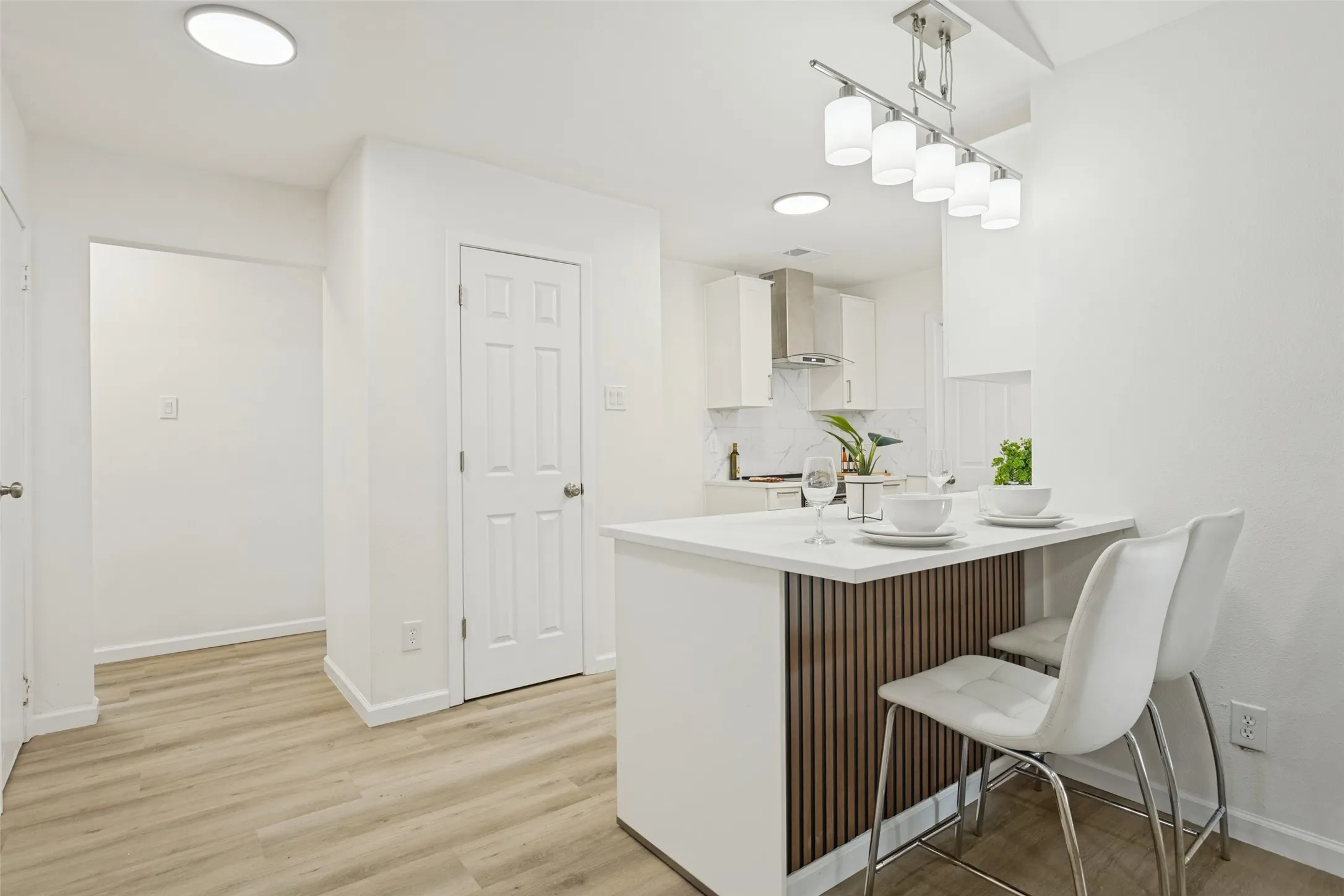 Kitchen featuring light-tone wood-finish flooring, recessed lighting, and a white countertop island with a wood-slat accent panel