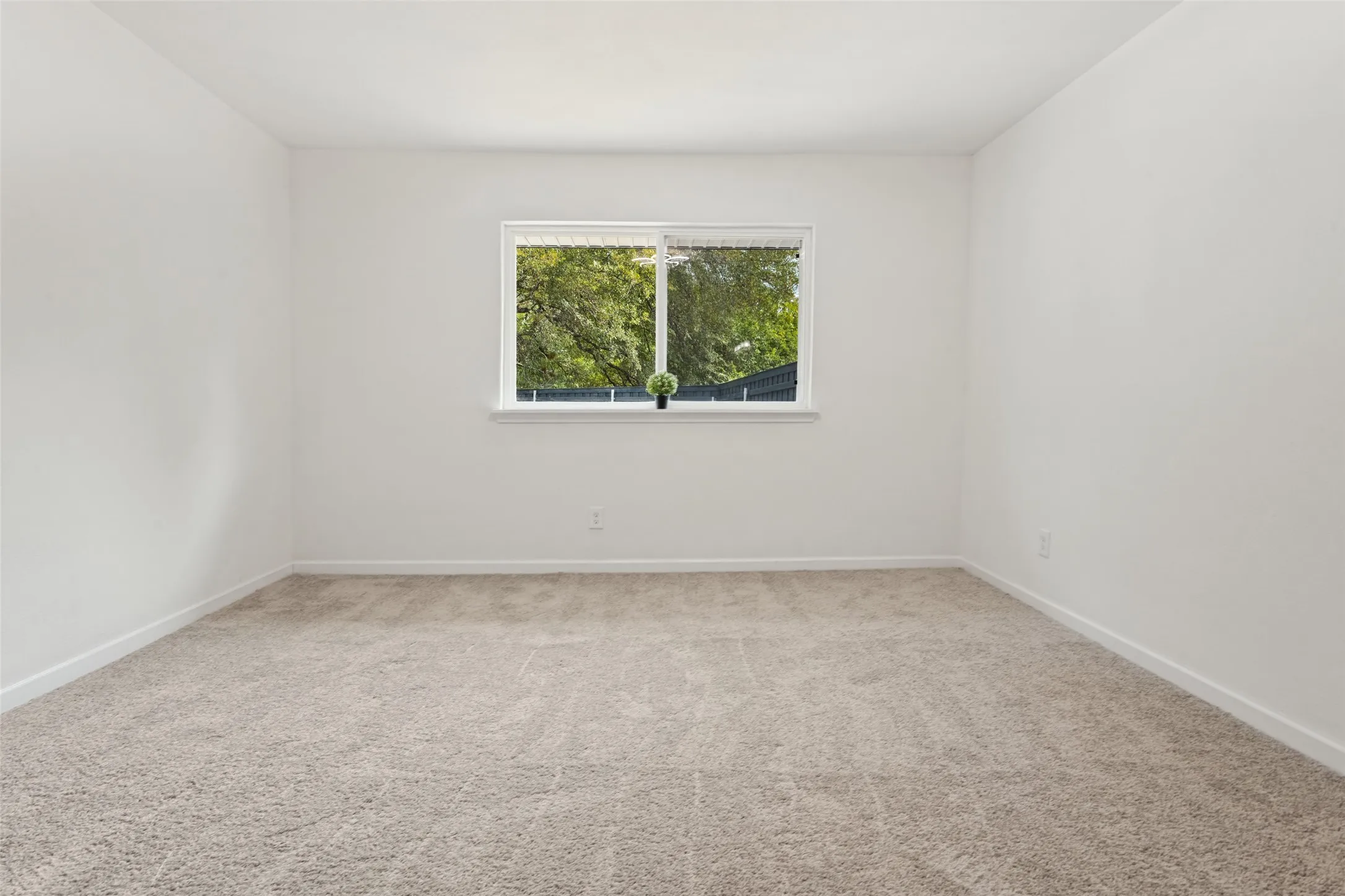 Neutral-toned carpeting, white walls, and a window with white trim