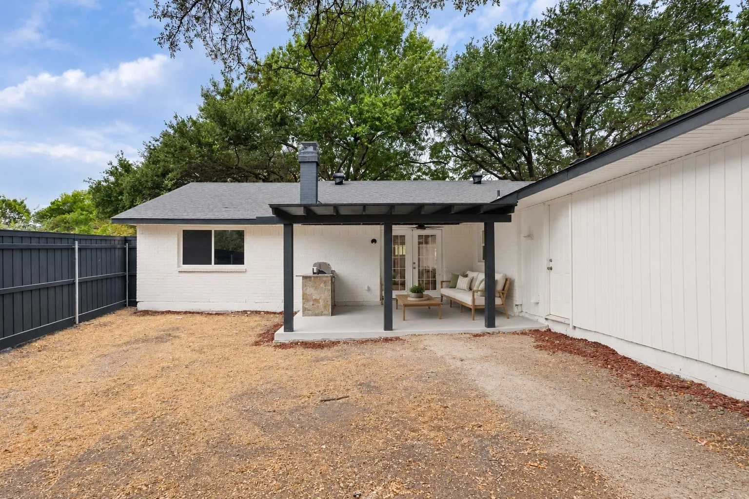 Covered patio with concrete flooring, stone-finish outdoor grill station, and exterior French doors