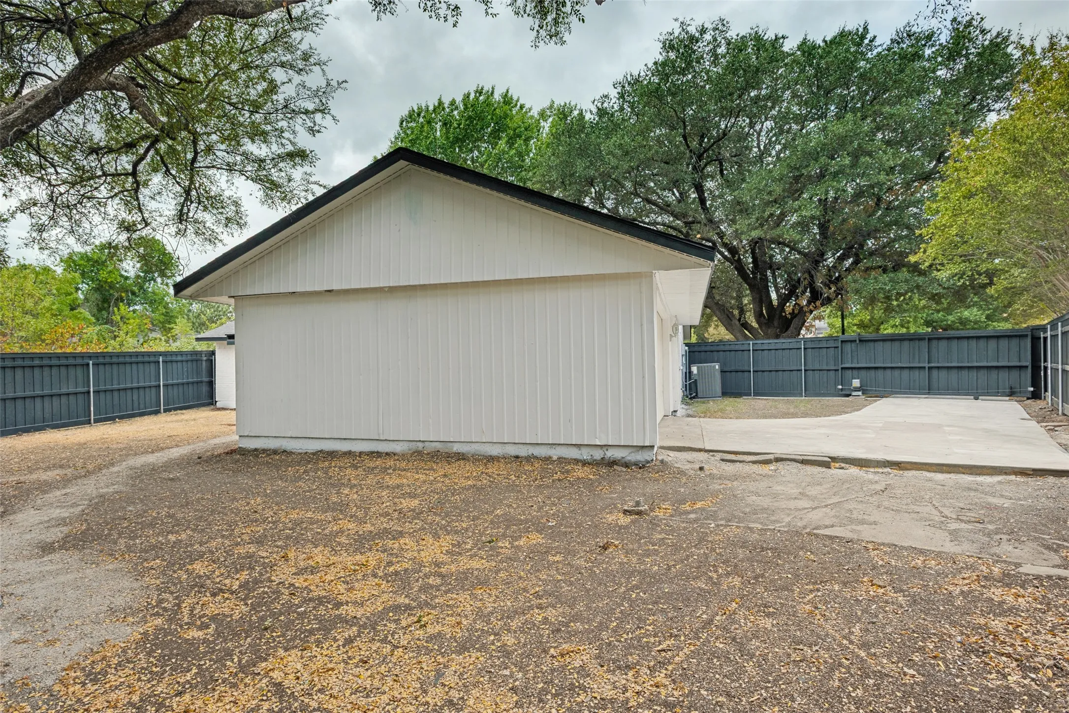 Side exterior featuring white vertical siding, black trim, and a concrete pad