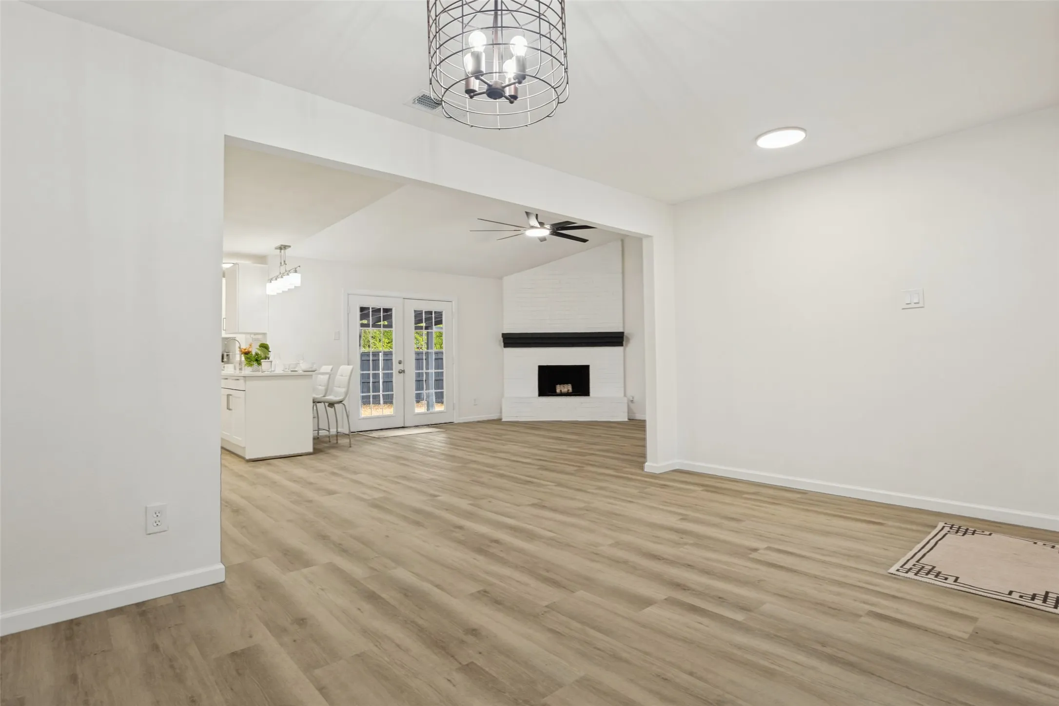 Wood-finish flooring throughout, recessed lighting, and a modern caged chandelier