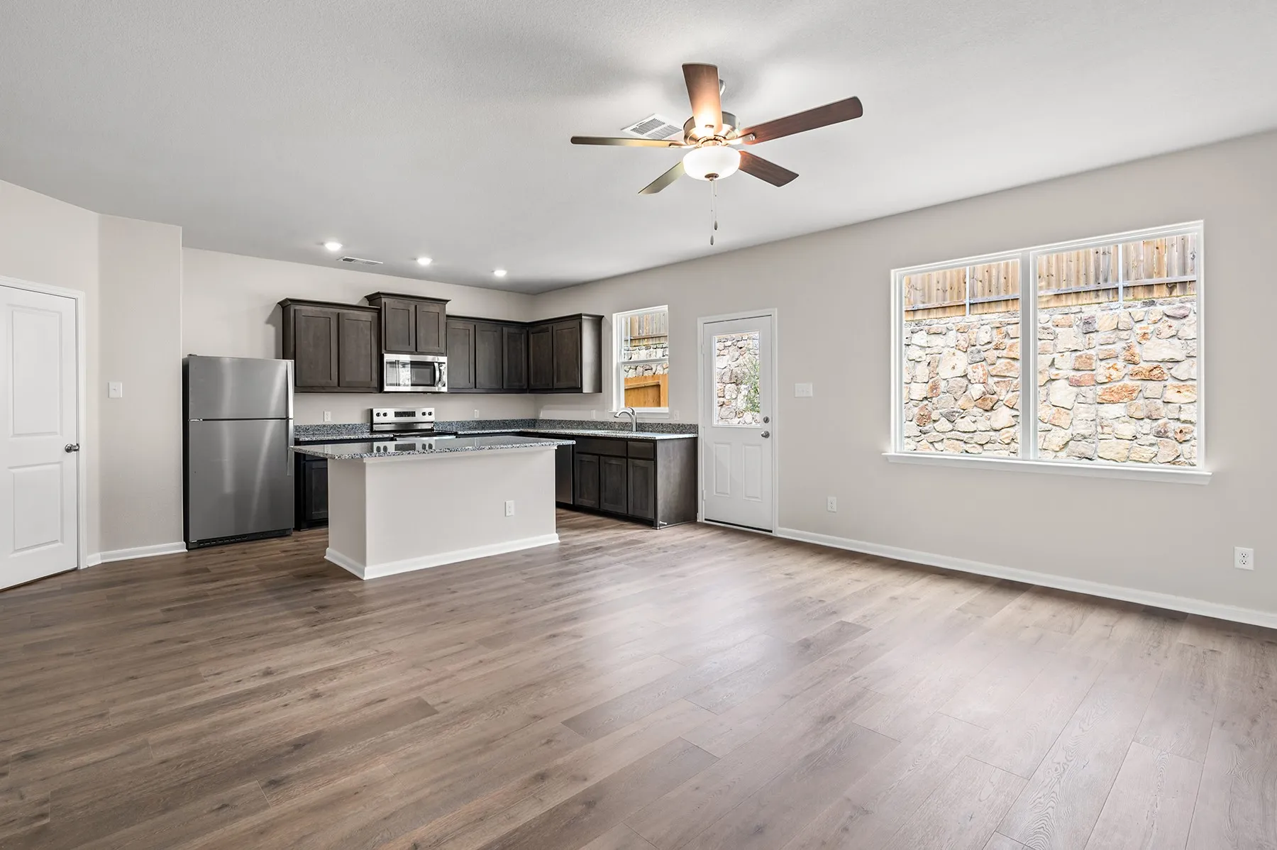 Kitchen with stainless steel appliances, a center island, dark brown cabinets, light wood finished floors, and a ceiling fan