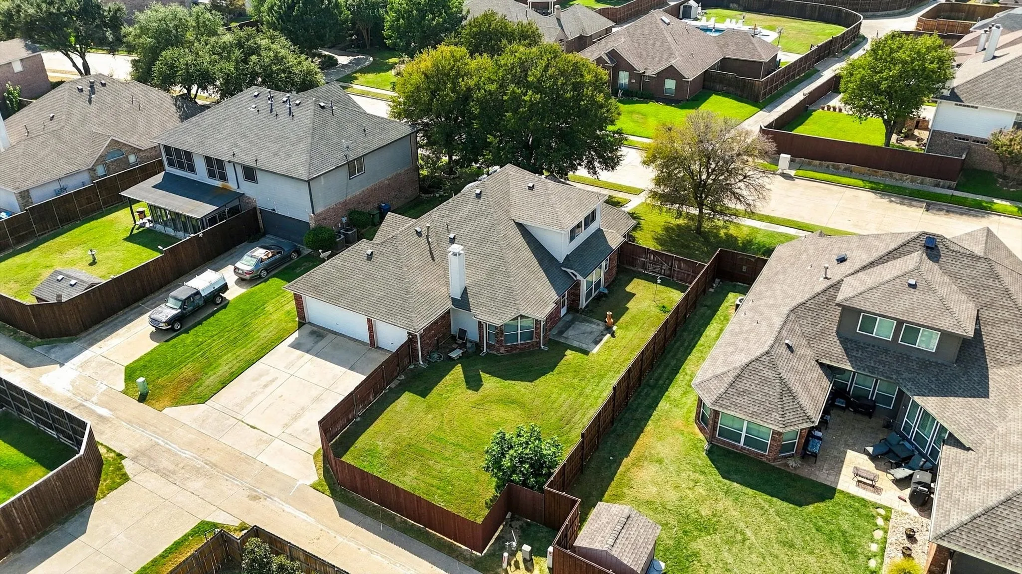 Brick exterior, attached garage, fenced backyard, mature landscaping, and an outdoor patio area