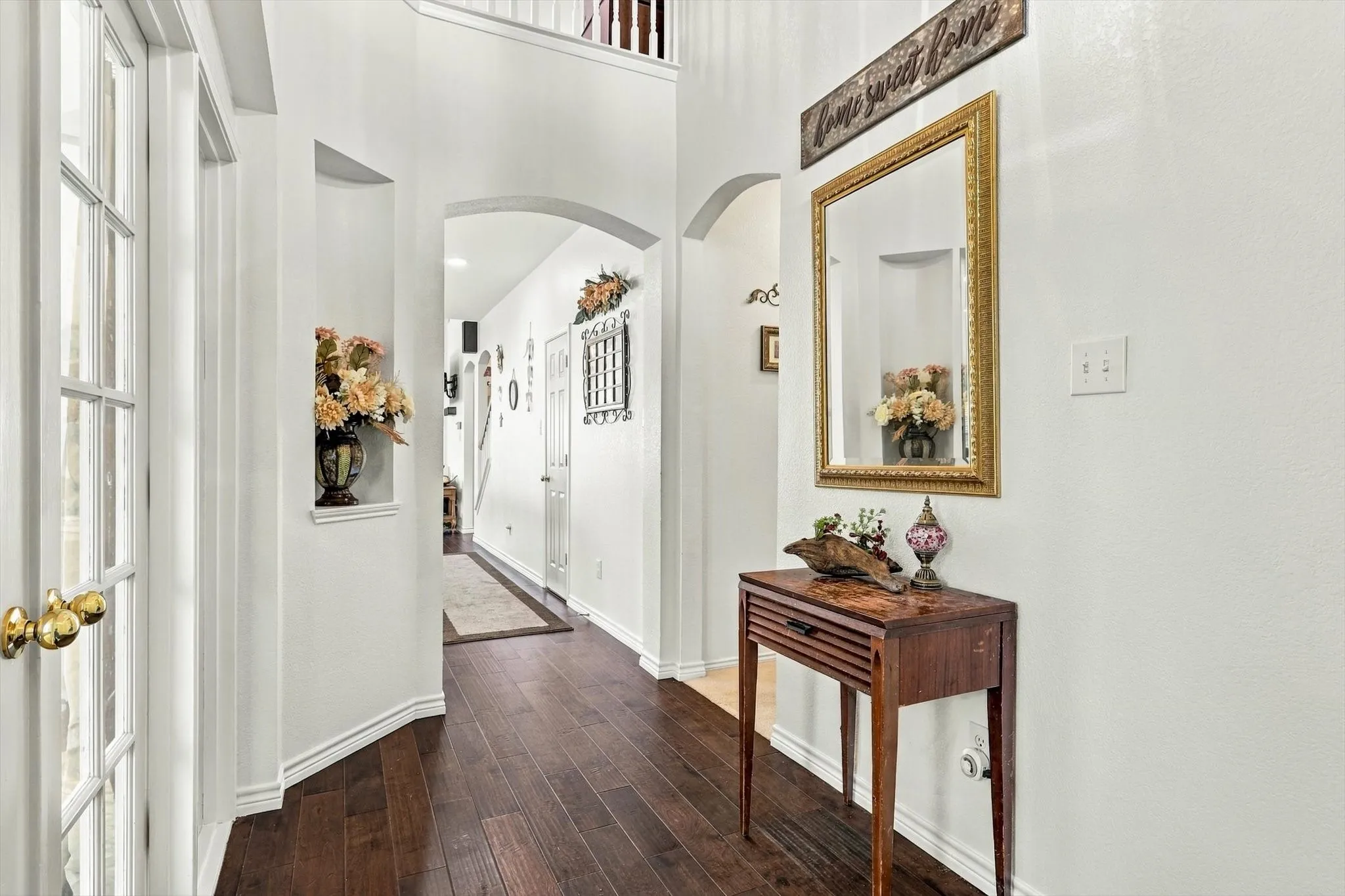 Hardwood flooring throughout, arched doorways, white interior walls, and a built-in wall niche