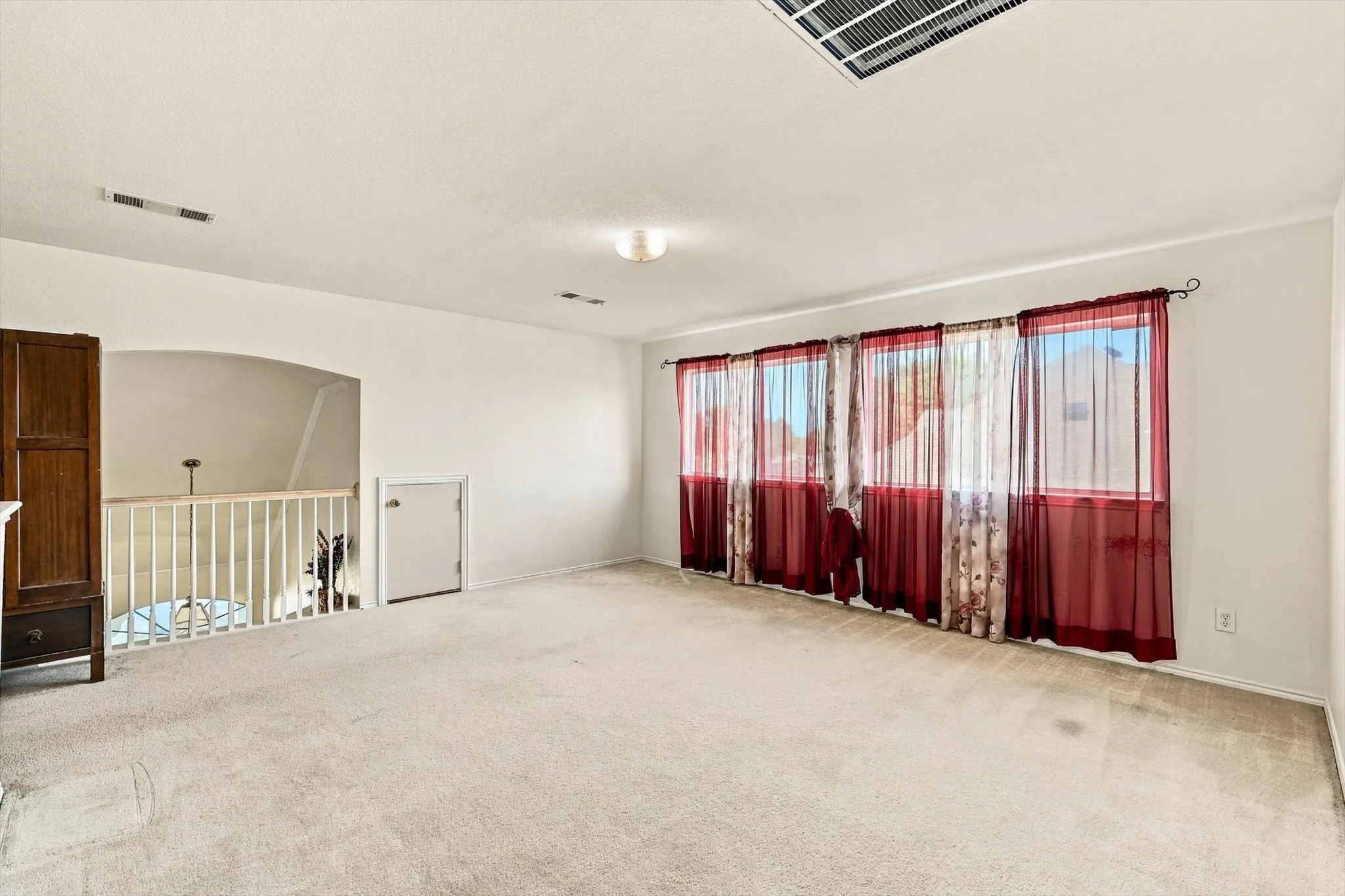 Carpeted room with multiple windows, recessed lighting, and a white railing