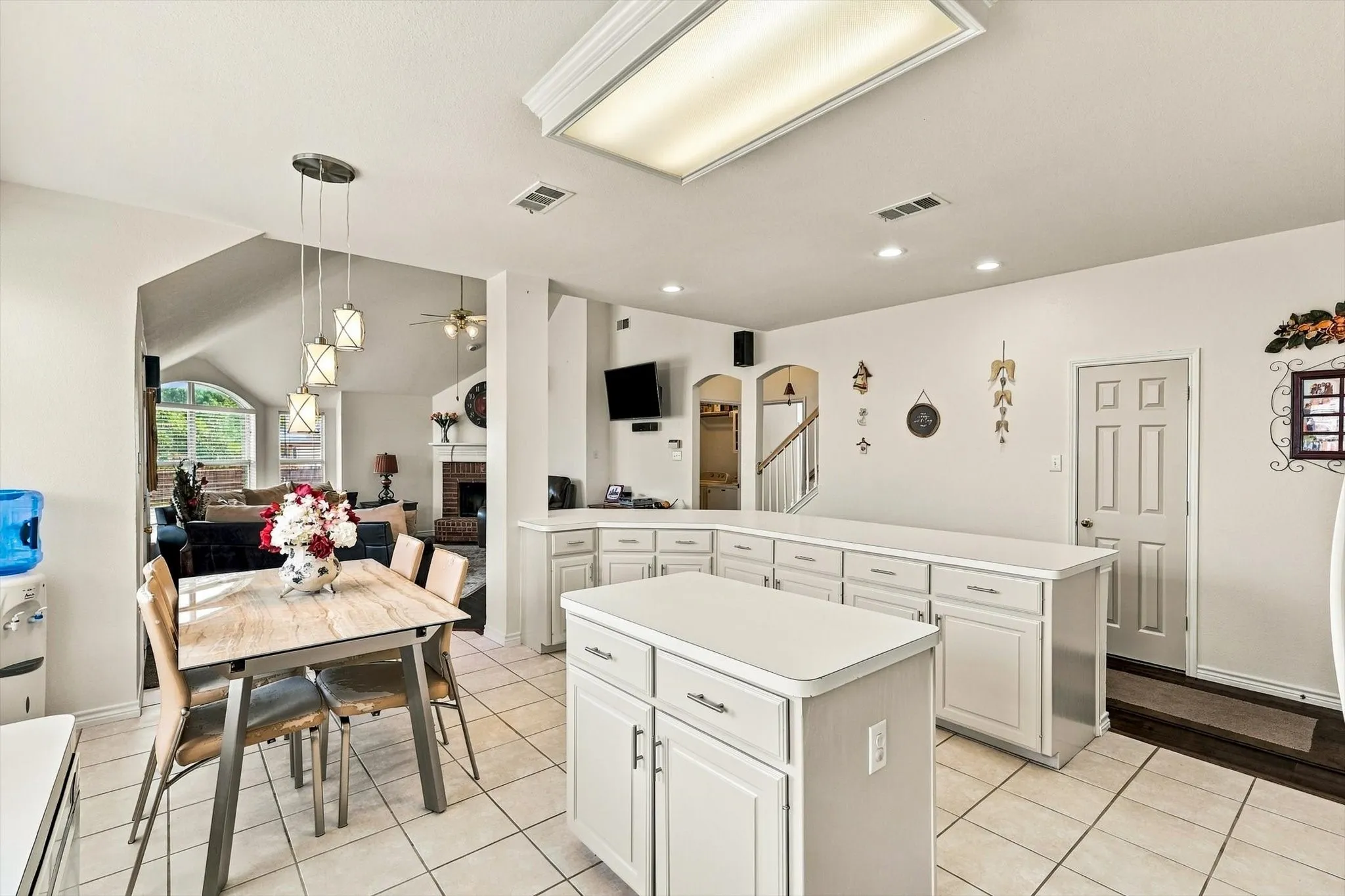 Kitchen featuring an island, white cabinetry, light-toned tile flooring, and recessed lighting