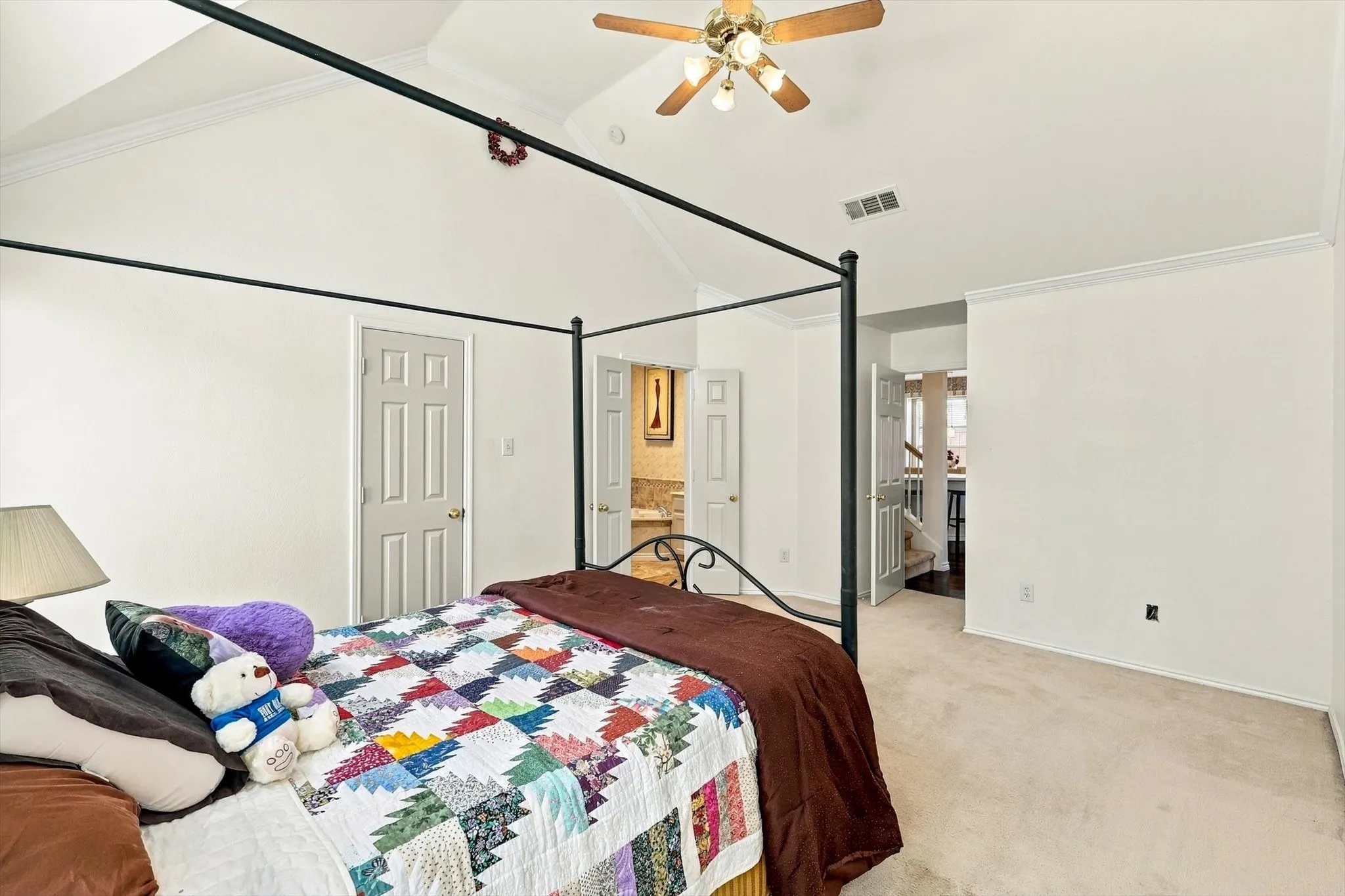 Vaulted ceiling with a ceiling fan, crown molding, and neutral-toned carpet flooring