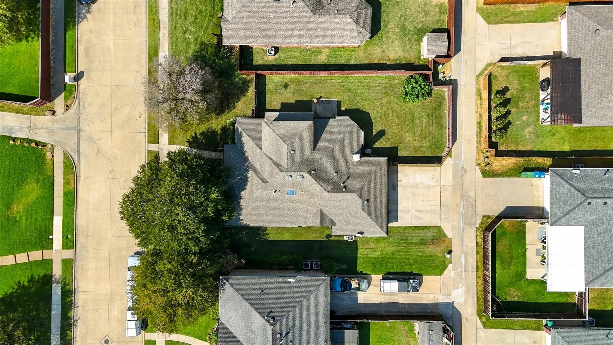 Property features a dark gray shingle roof, green lawn, and mature trees