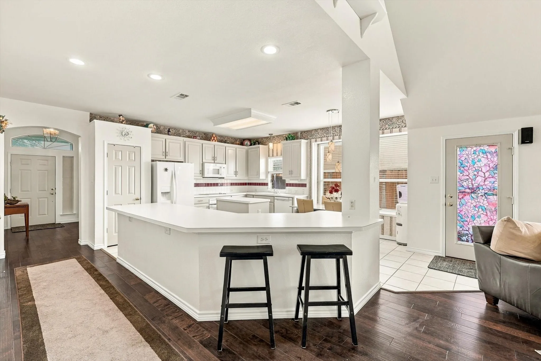Kitchen featuring white cabinetry, white appliances, a center island, and recessed lighting