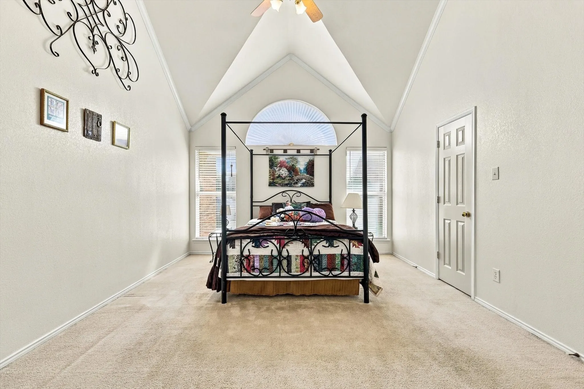 Vaulted ceiling with a ceiling fan, arched transom window, dual pane windows with blinds, and neutral carpet flooring
