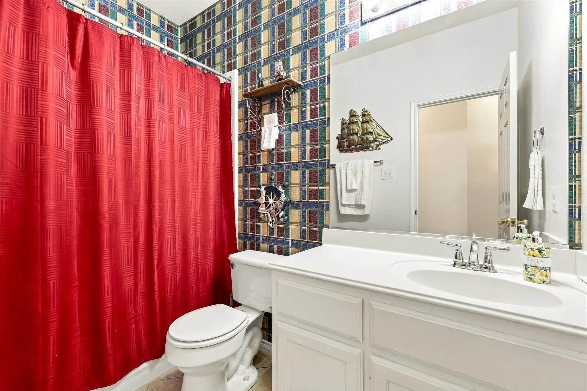 White vanity with a single basin sink, chrome faucet, and expansive wall-mounted mirror