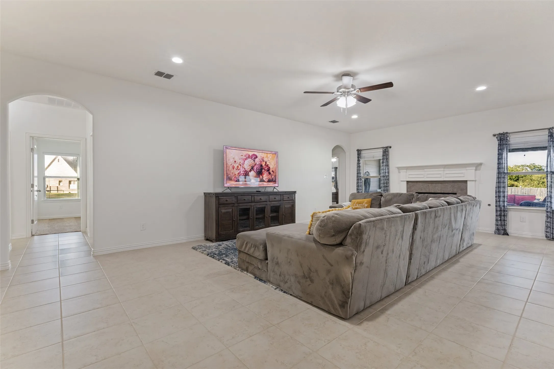 Spacious living area featuring tile flooring, recessed lighting, an arched doorway, and a ceiling fan