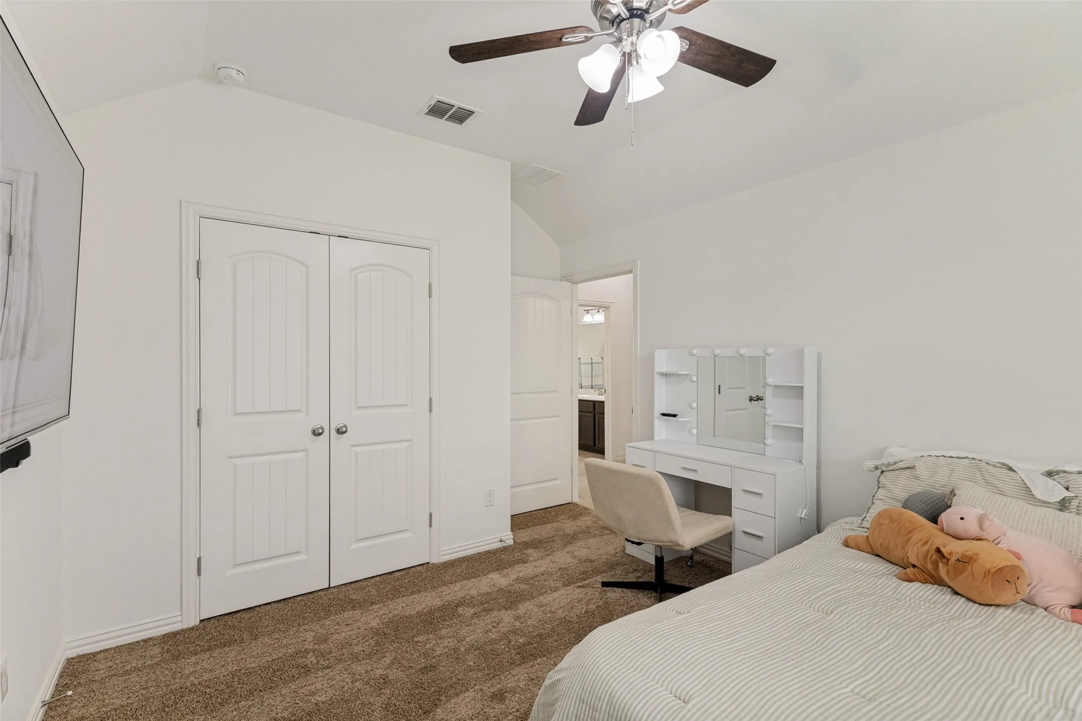 Vaulted ceiling with a ceiling fan, white paneled bifold doors, and neutral carpet flooring