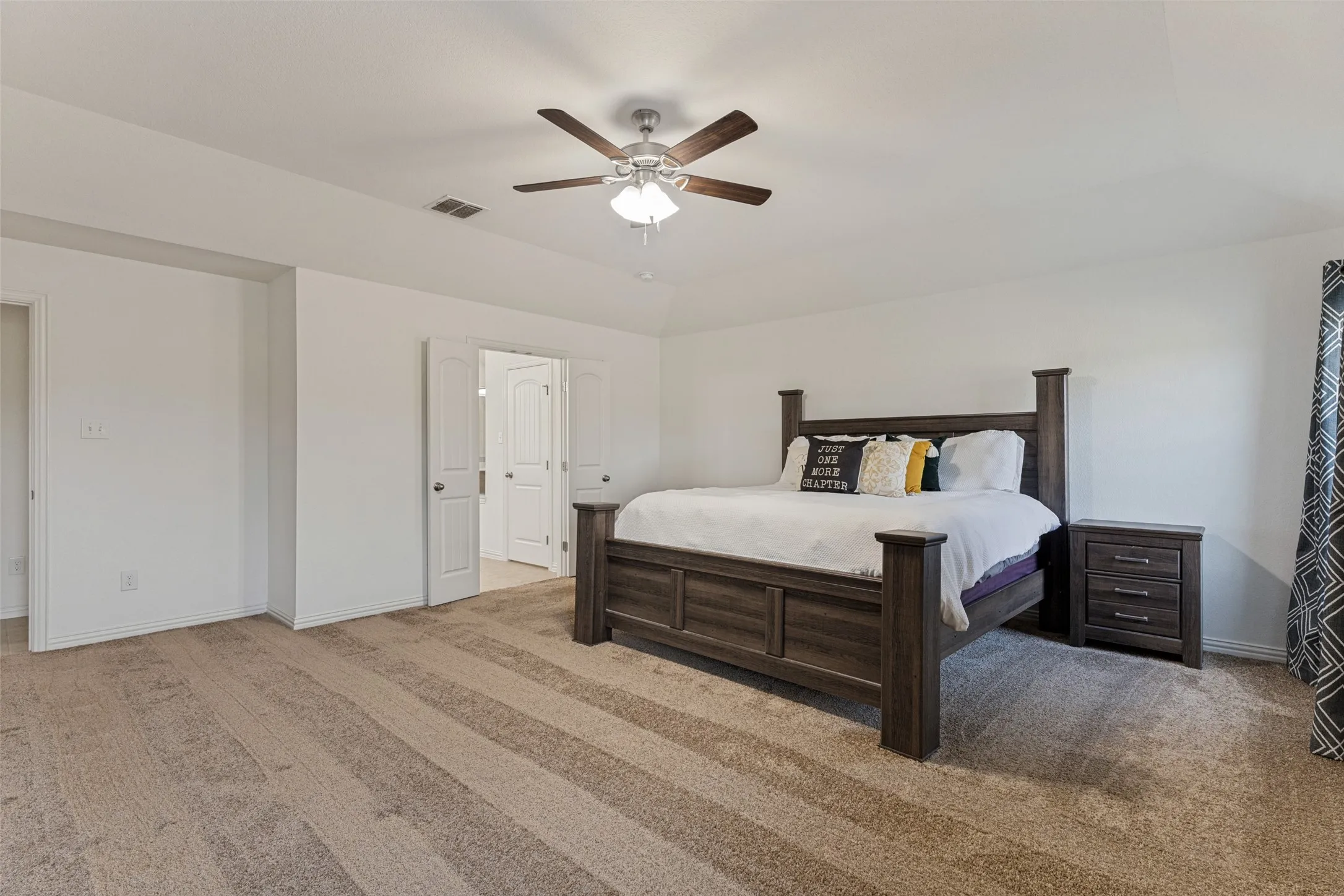 Expansive room with neutral carpeting and a ceiling fan
