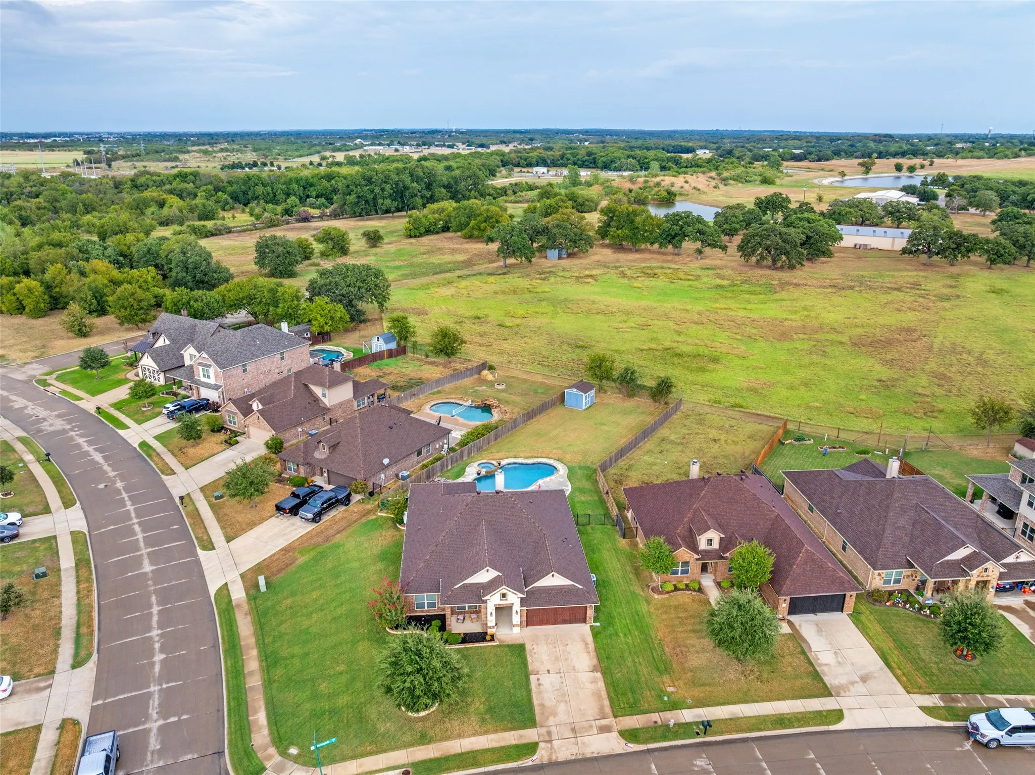 Residential street featuring single-family homes with private swimming pools and surrounding green spaces