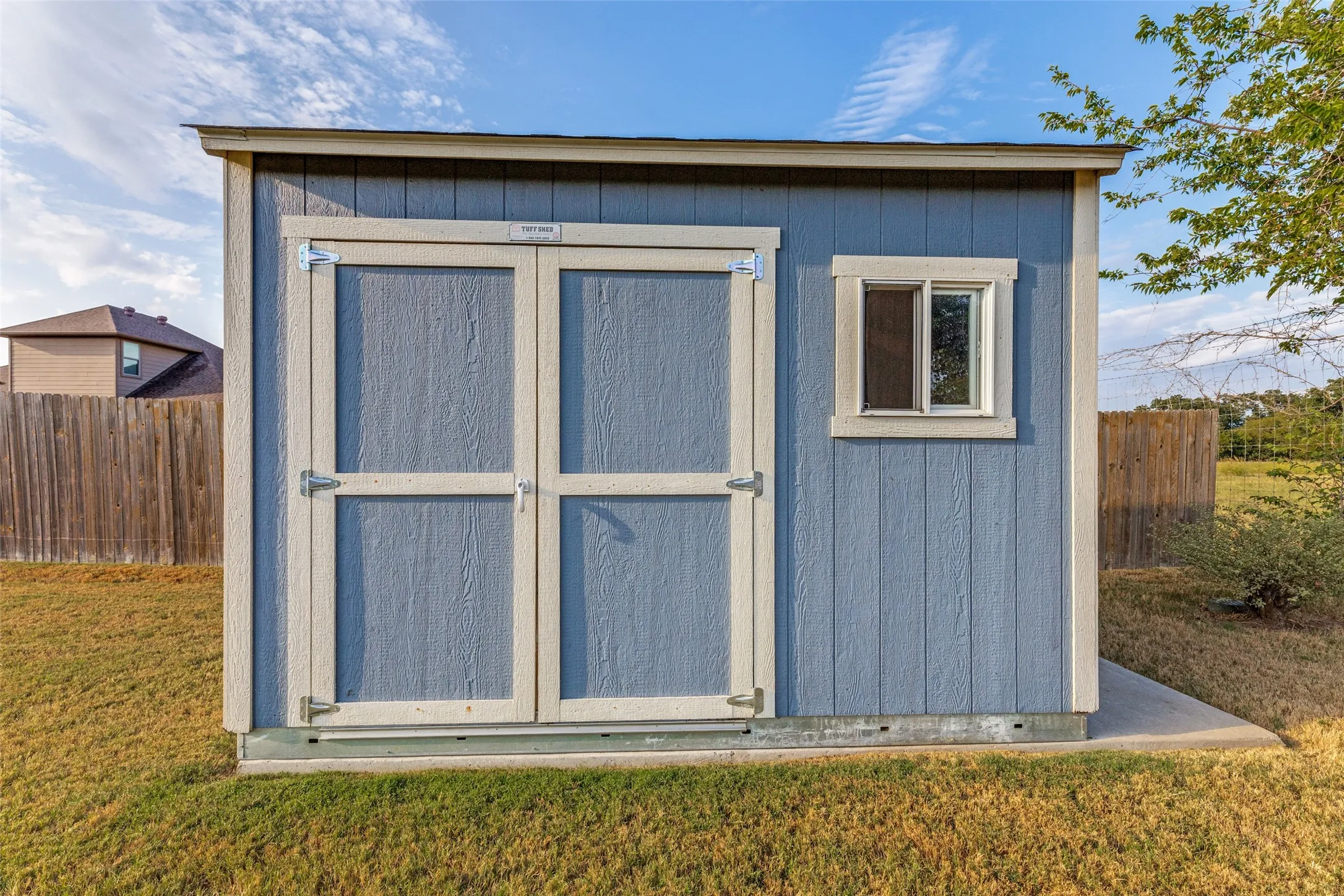 Detached storage shed featuring a dual-door entry, a single window, and a wood-panel exterior
