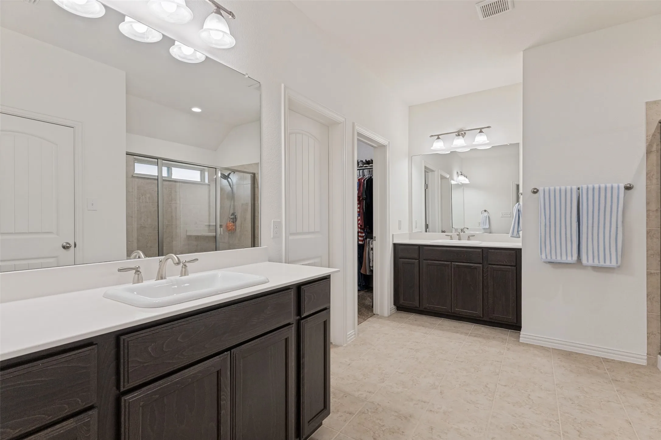 Dual dark wood-finish vanities with white countertops, integrated sinks, and brushed nickel fixtures