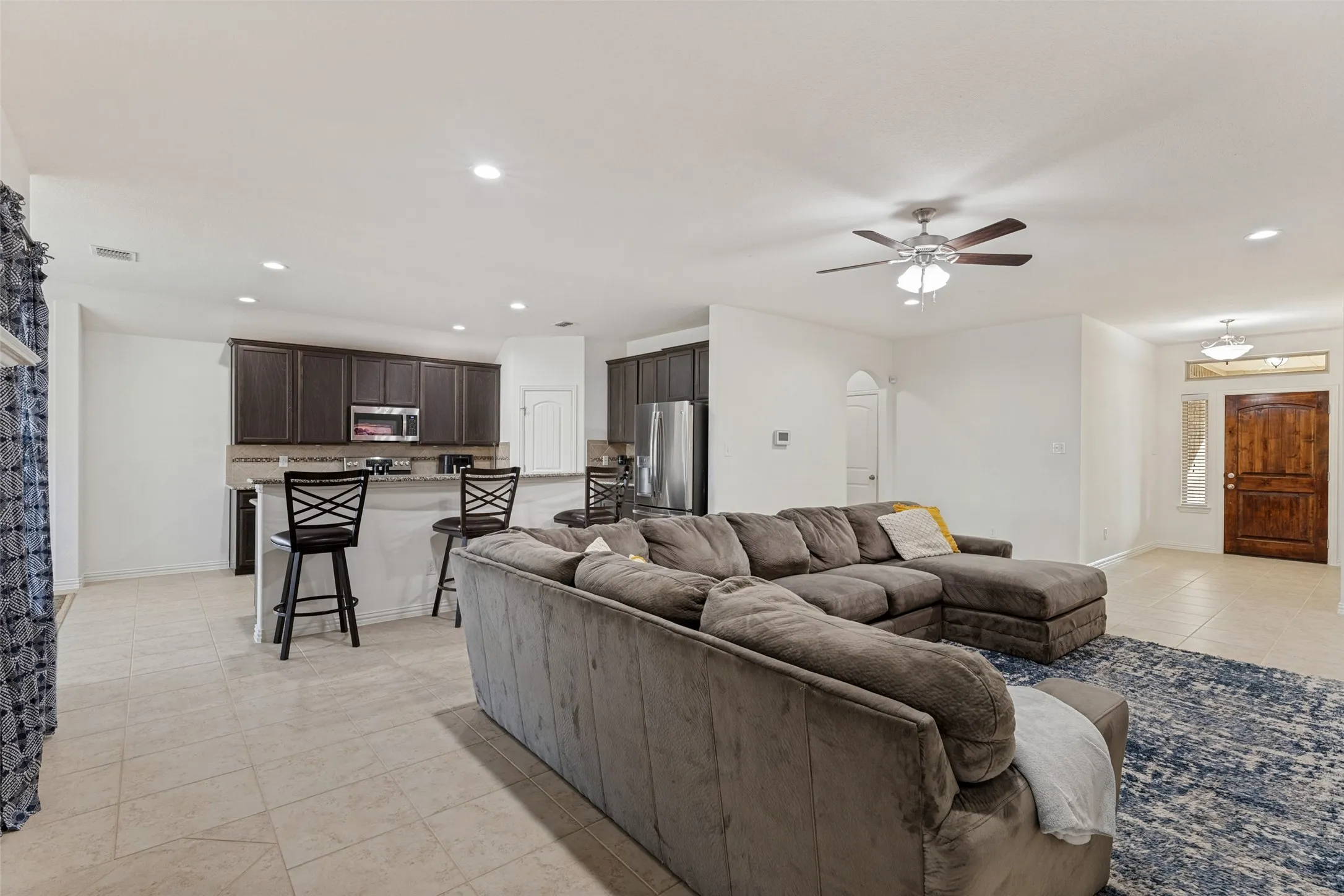 Open-concept living space with tile flooring, recessed lighting, and a ceiling fan