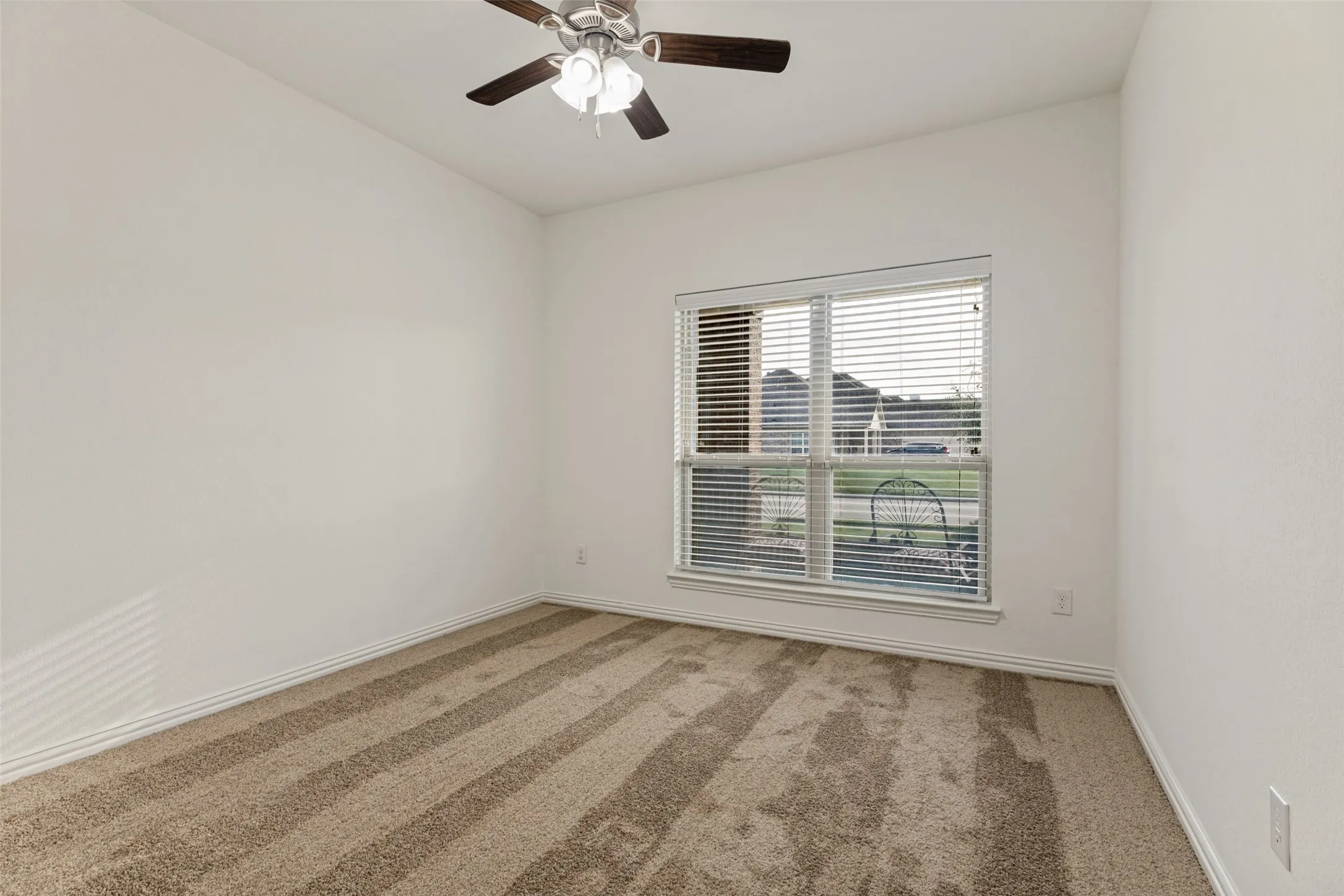 Room featuring neutral carpeting, a ceiling fan, and a window with horizontal blinds
