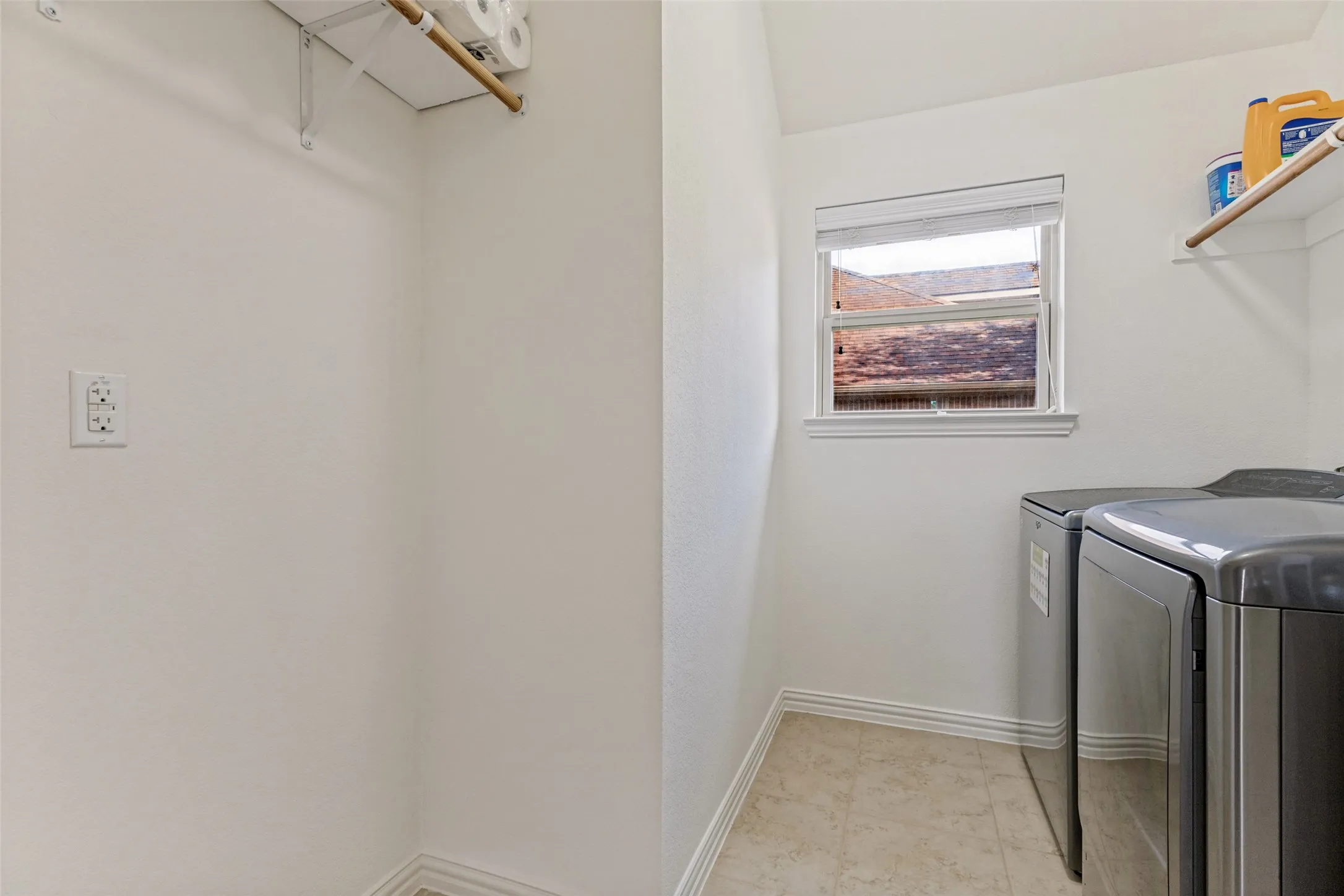 Utility space featuring neutral wall tones, window, tiled flooring, and built-in shelving