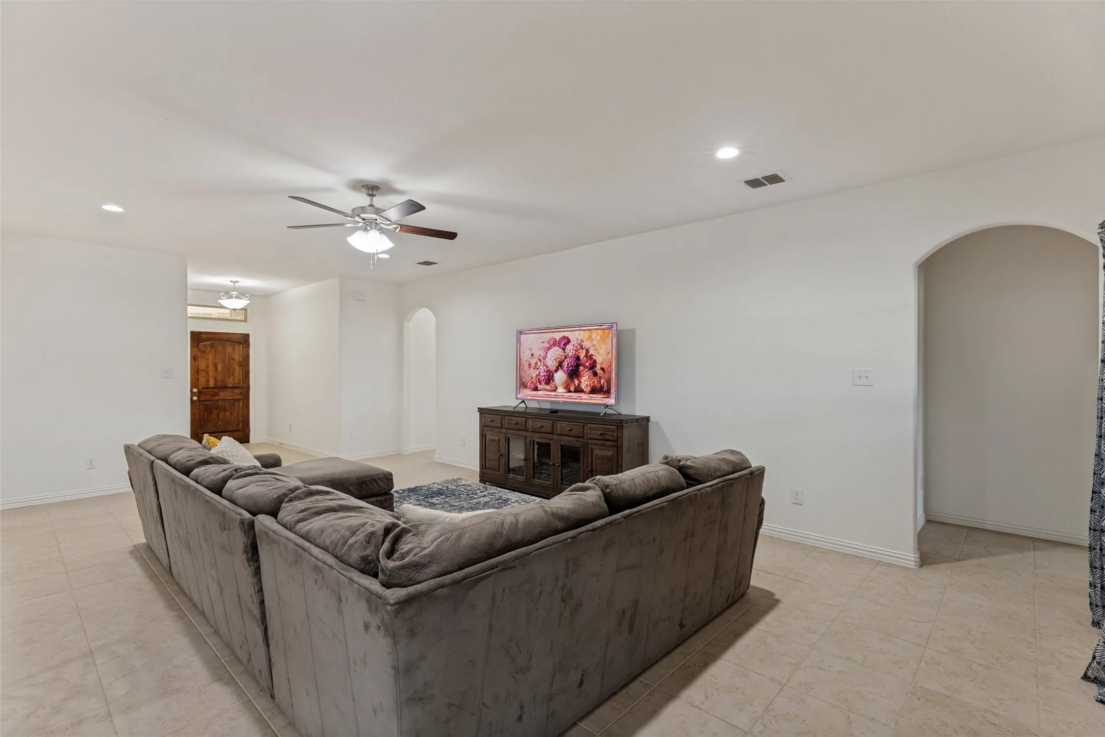 Recessed lighting, ceiling fan, arched doorway, tile flooring, and a wood-finish entry door