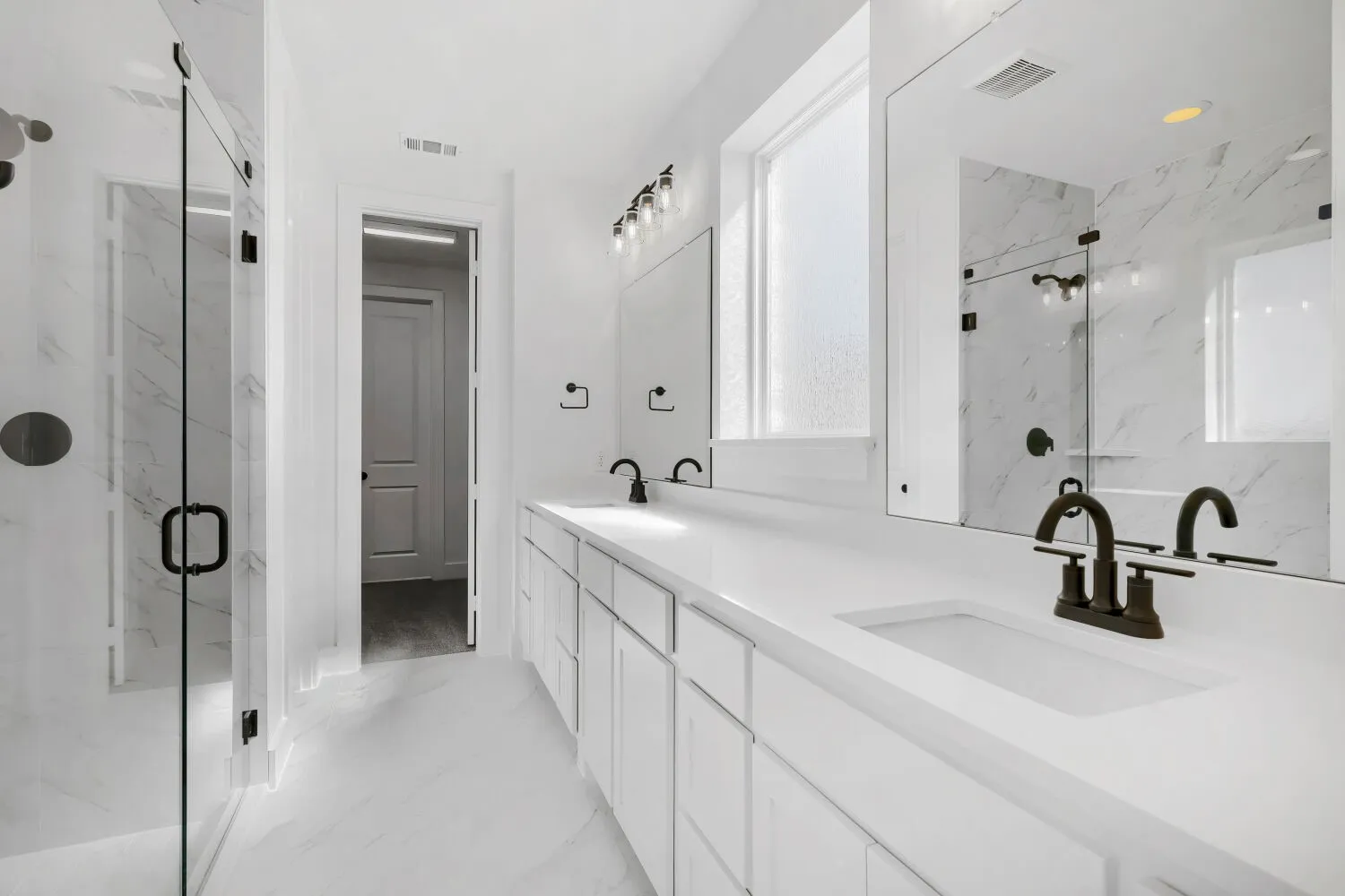 Spa-inspired primary bathroom featuring dual vanities with white cabinetry and quartz countertops, polished nickel faucetry, and an oversized walk-in shower with frameless glass enclosure and marble tile surround