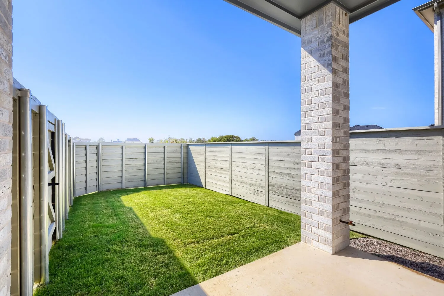 Private backyard with a manicured lawn, concrete patio, and perimeter fencing